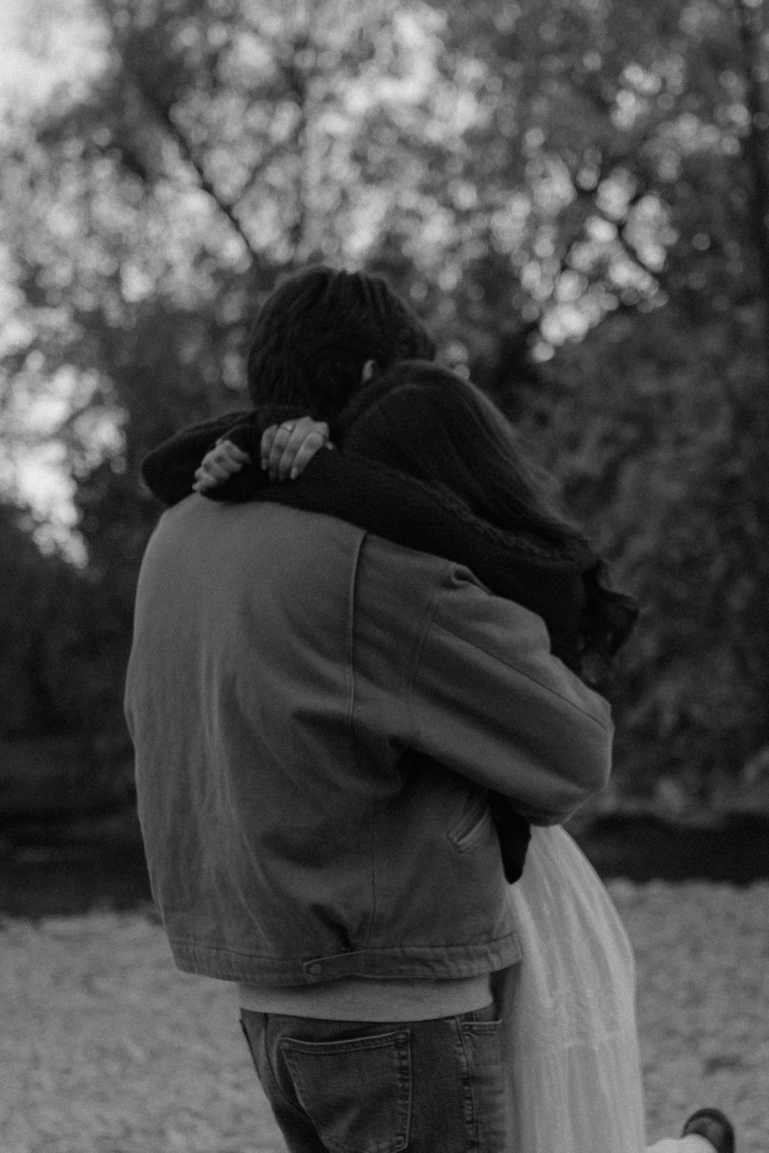Black and white photo capturing an emotional embrace between couple in nature.