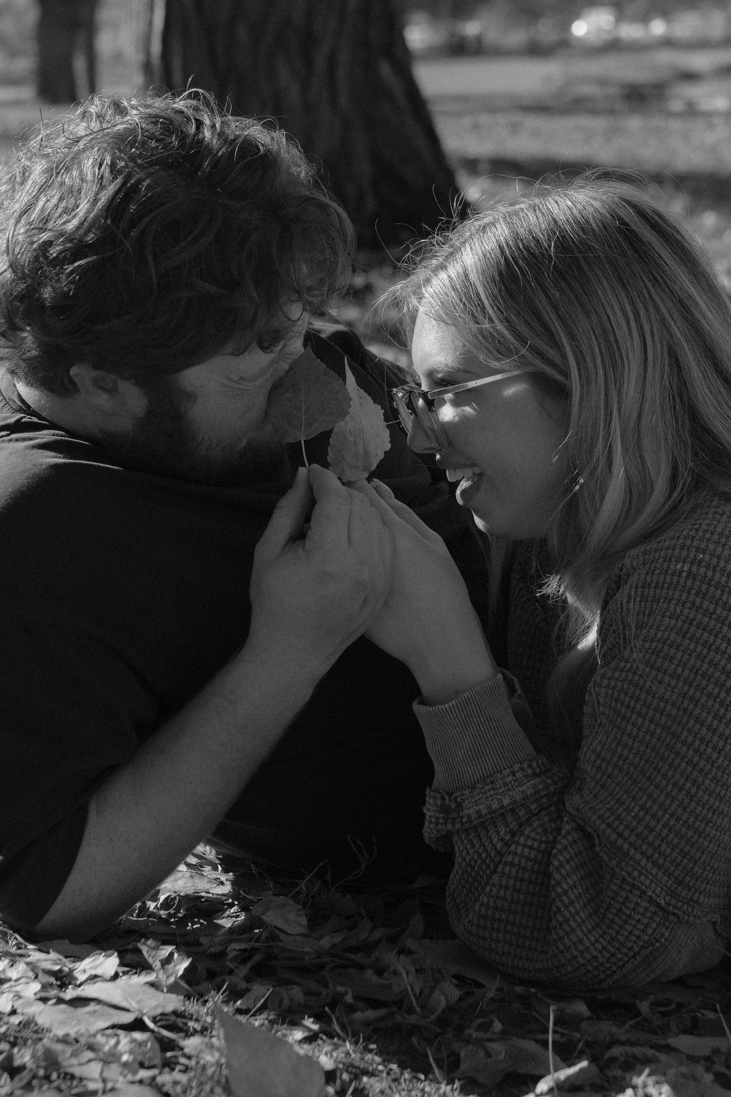 An intimate close-up moment between two people lying on autumn leaves.