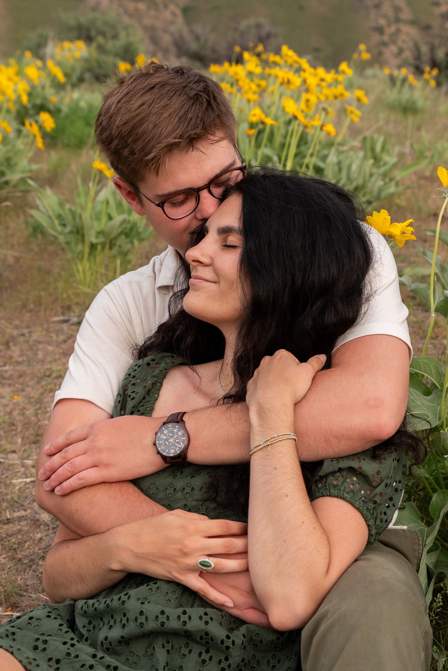 A romantic couple embraces among blooming yellow daffodils in a garden setting on a warm day.