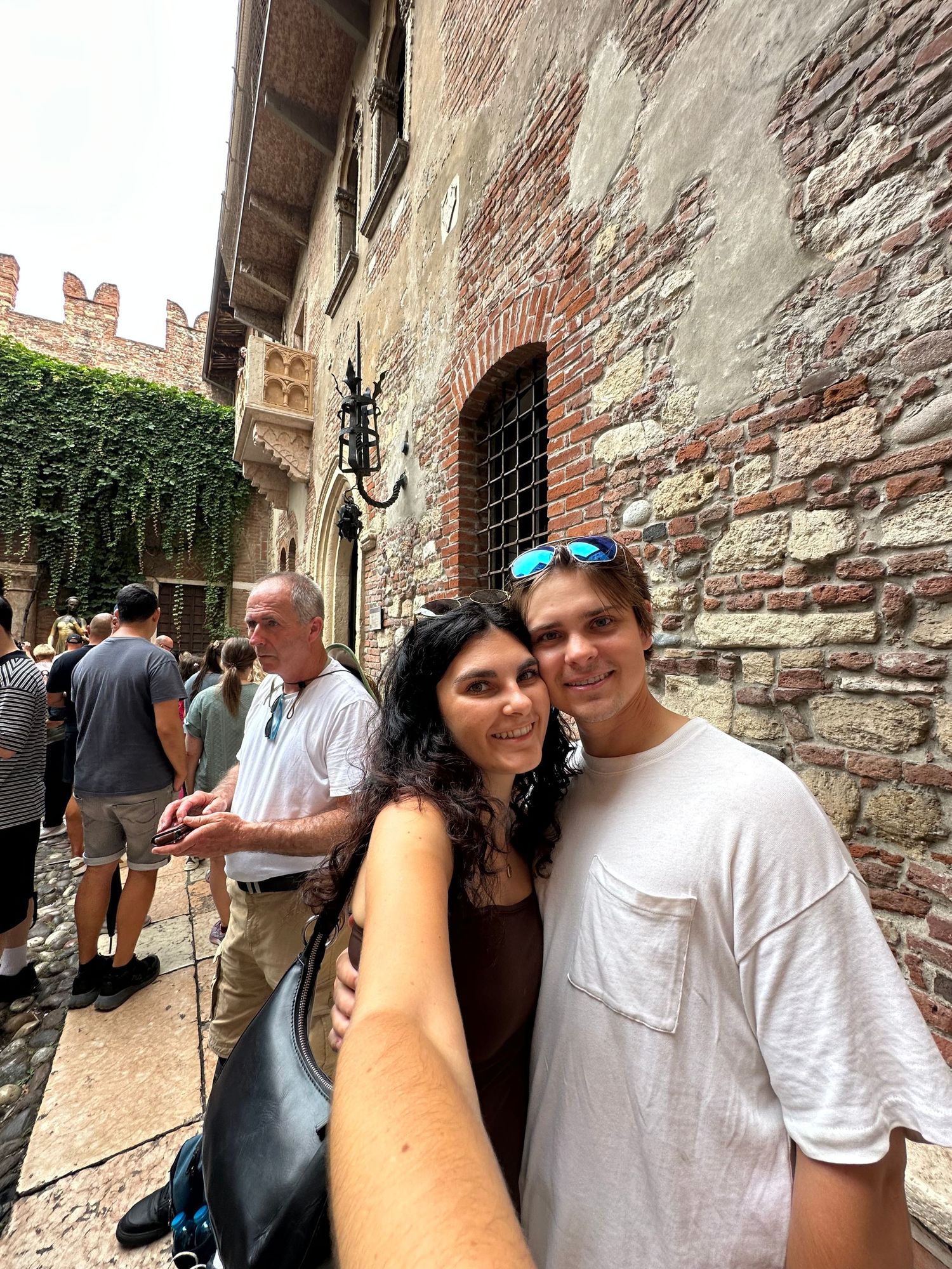 Tourist selfies taken against historic stone walls and architecture.