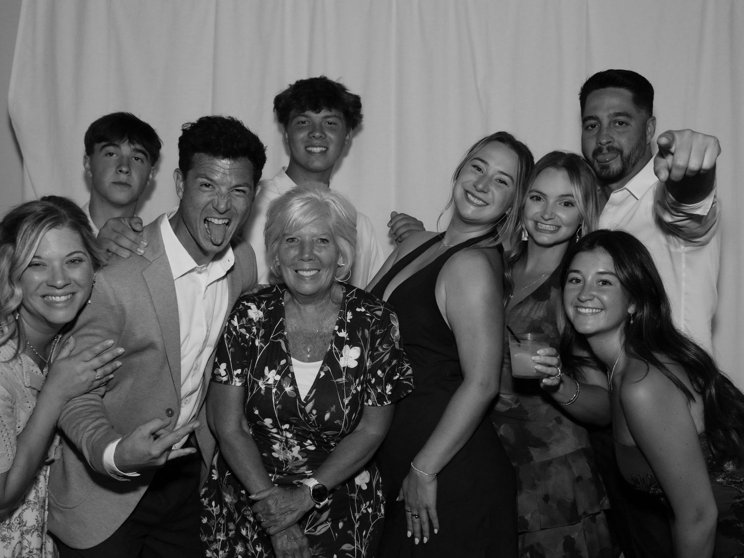 Black and white group photo of smiling family posing together at a formal event in front of white backdrop.