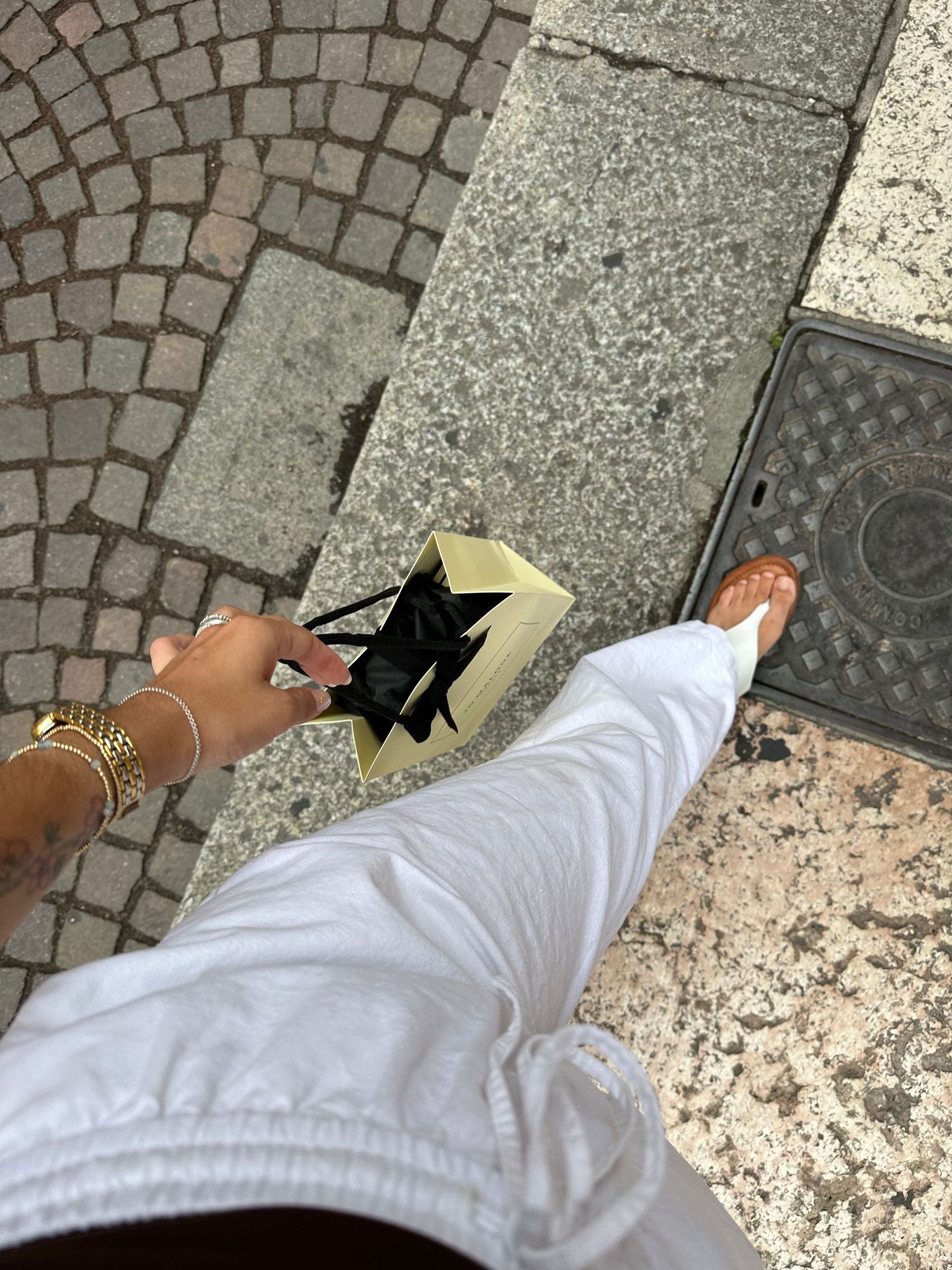 Close-up of hands placing something on cobblestone pavement.