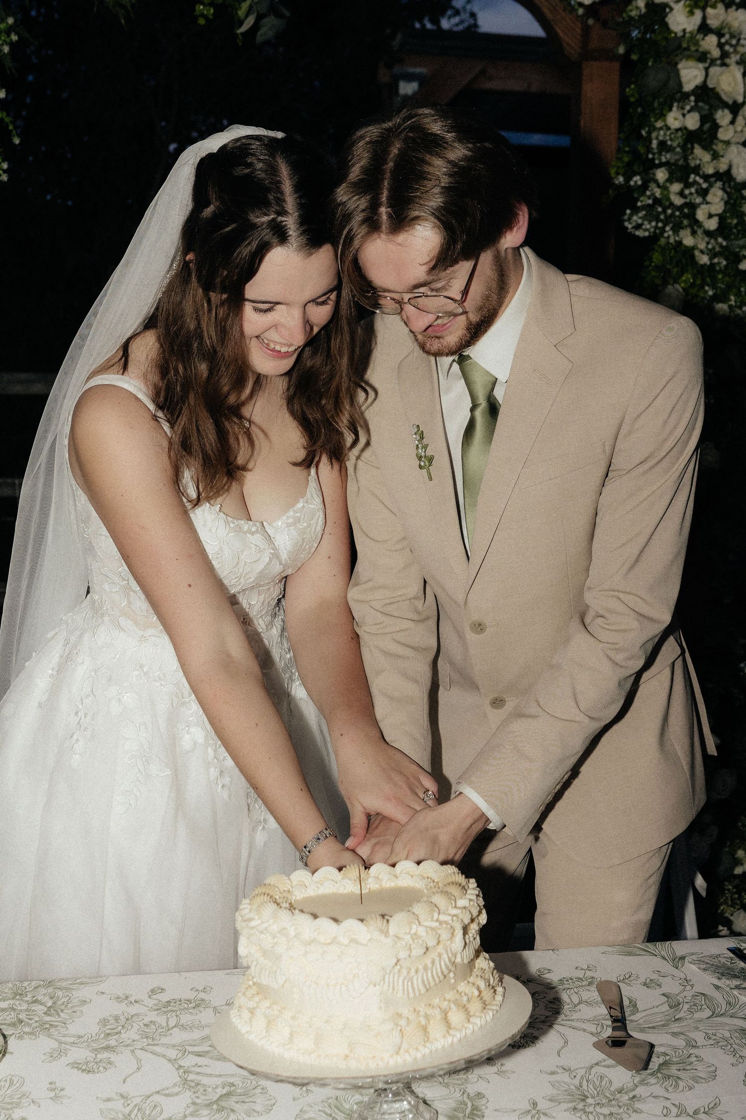 Newlyweds cutting their white wedding cake together at the reception.