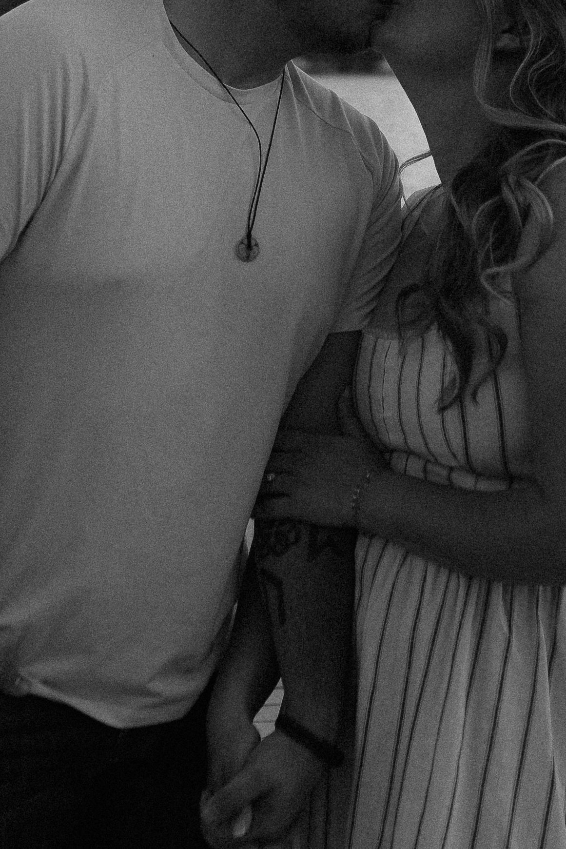Artistic black and white close-up of a couple in casual attire showing tender affection.