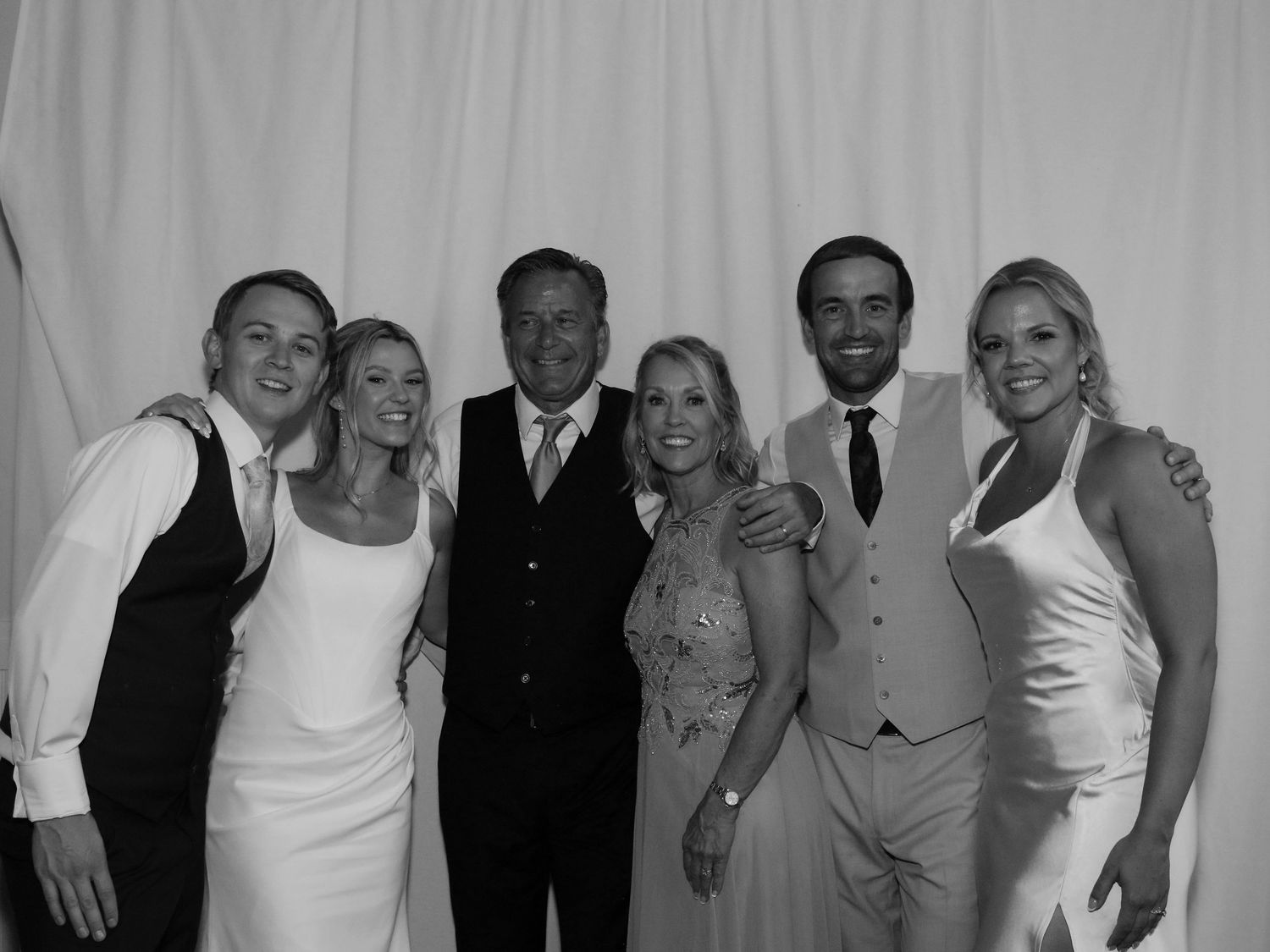 Black and white photo of six elegantly dressed people posing together at a formal wedding celebration.