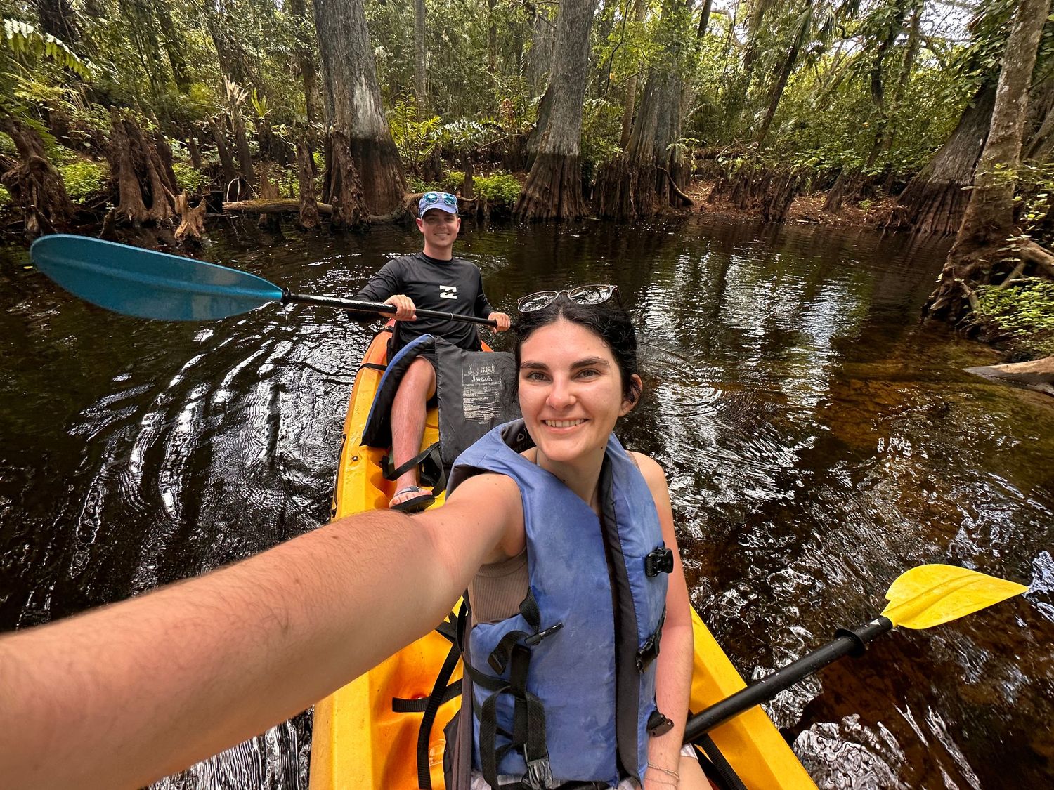 Yellow kayaks floating on calm water surrounded by trees and greenery.