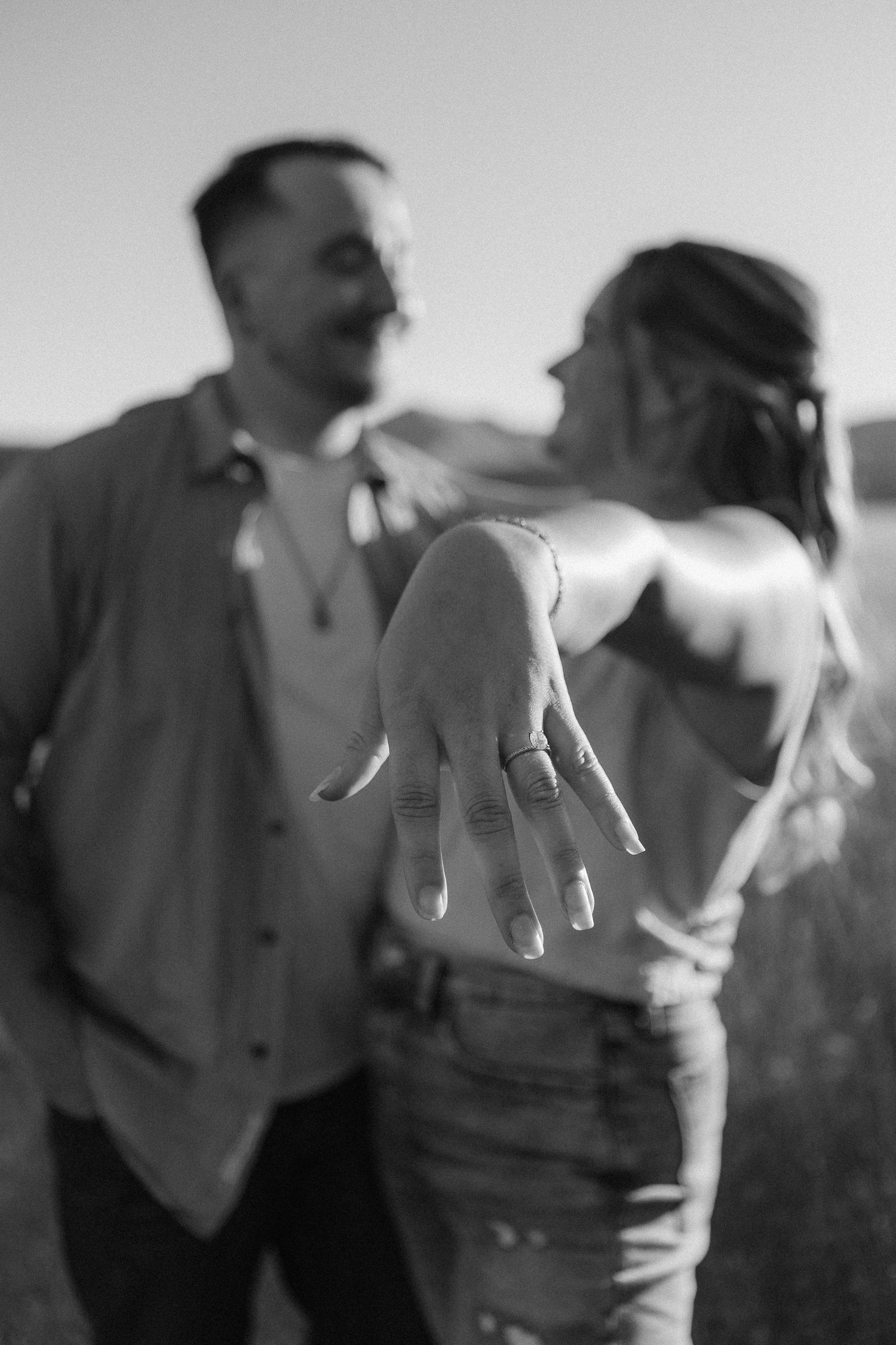 Close-up shot of an engagement ring being shown off against a mountain backdrop.