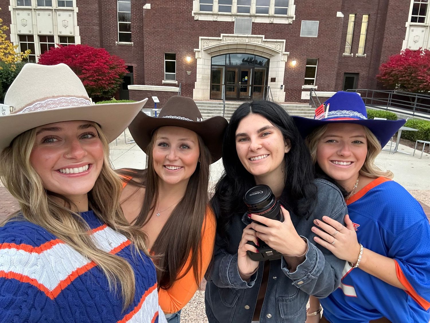 Friends wearing casual attire and hats gathered outside a brick building.