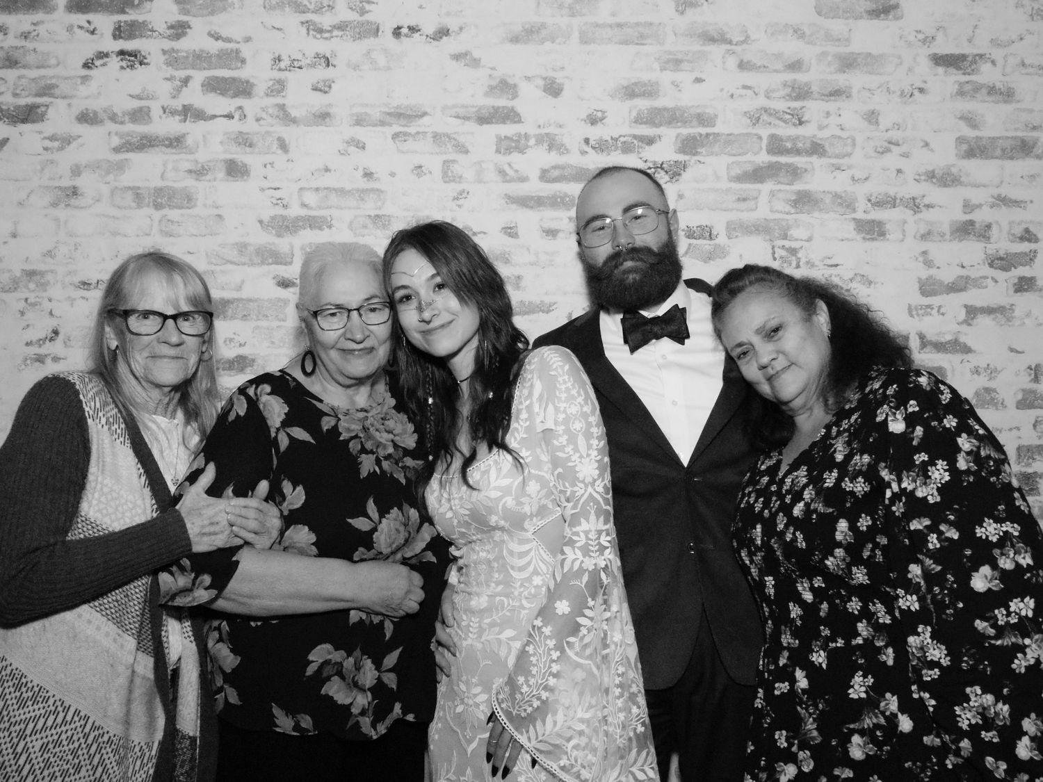 Group photo against exposed brick wall at formal event.