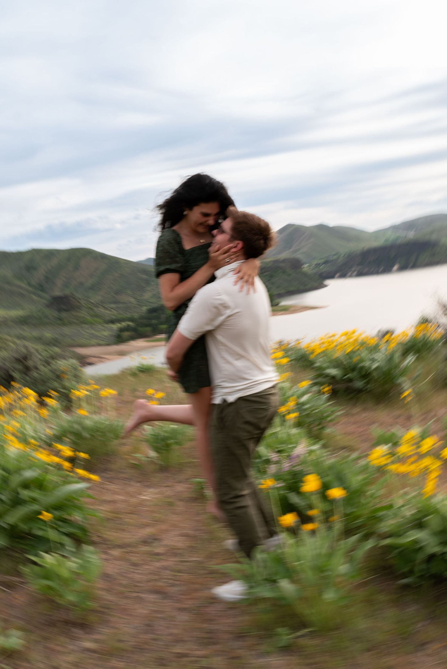 A romantic sequence of couples embracing and spinning on a mountain trail surrounded by blooming yellow wildflowers.