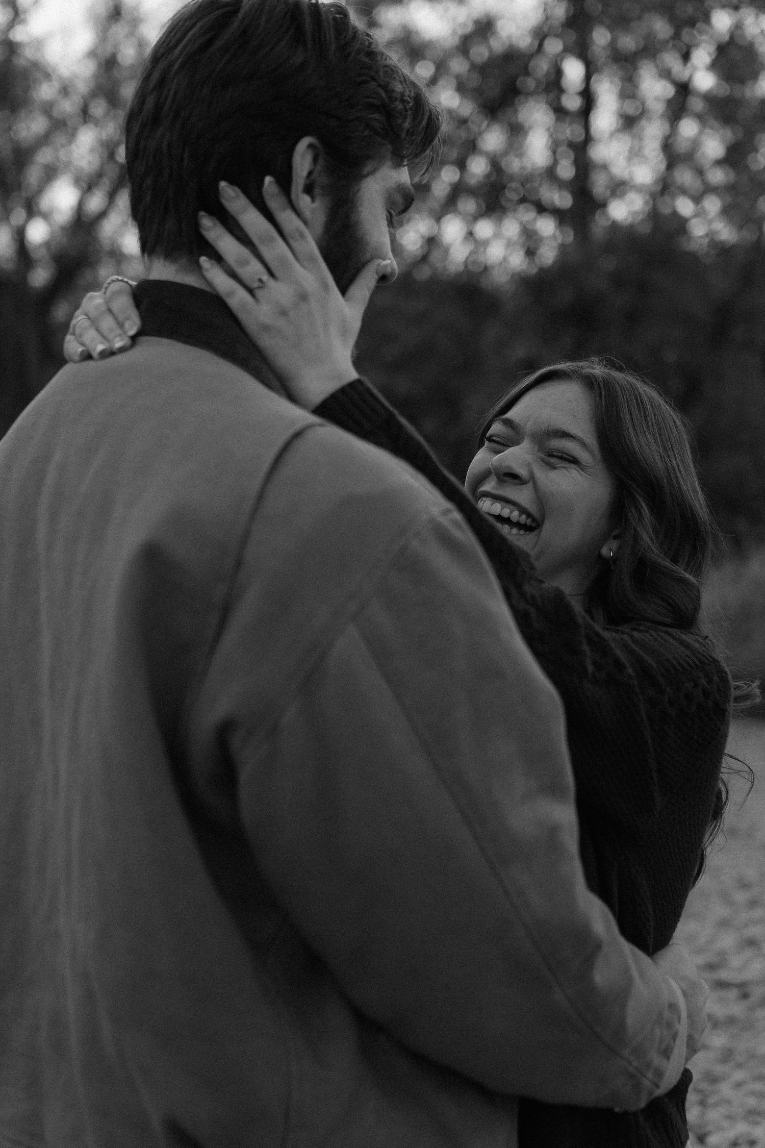 Intimate black and white portrait of couple sharing a joyful moment outdoors.