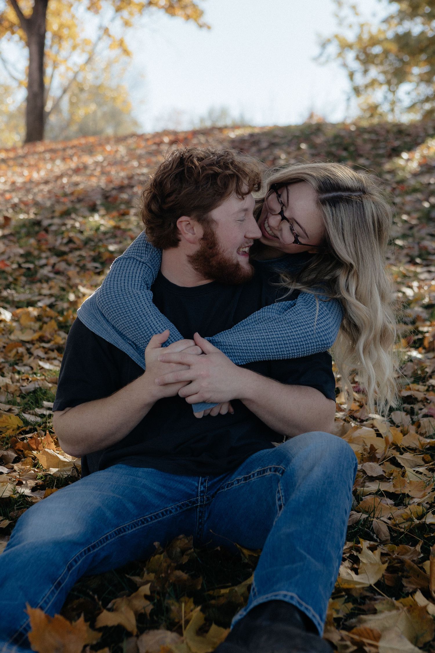 Couple sharing an intimate moment among fallen autumn leaves.