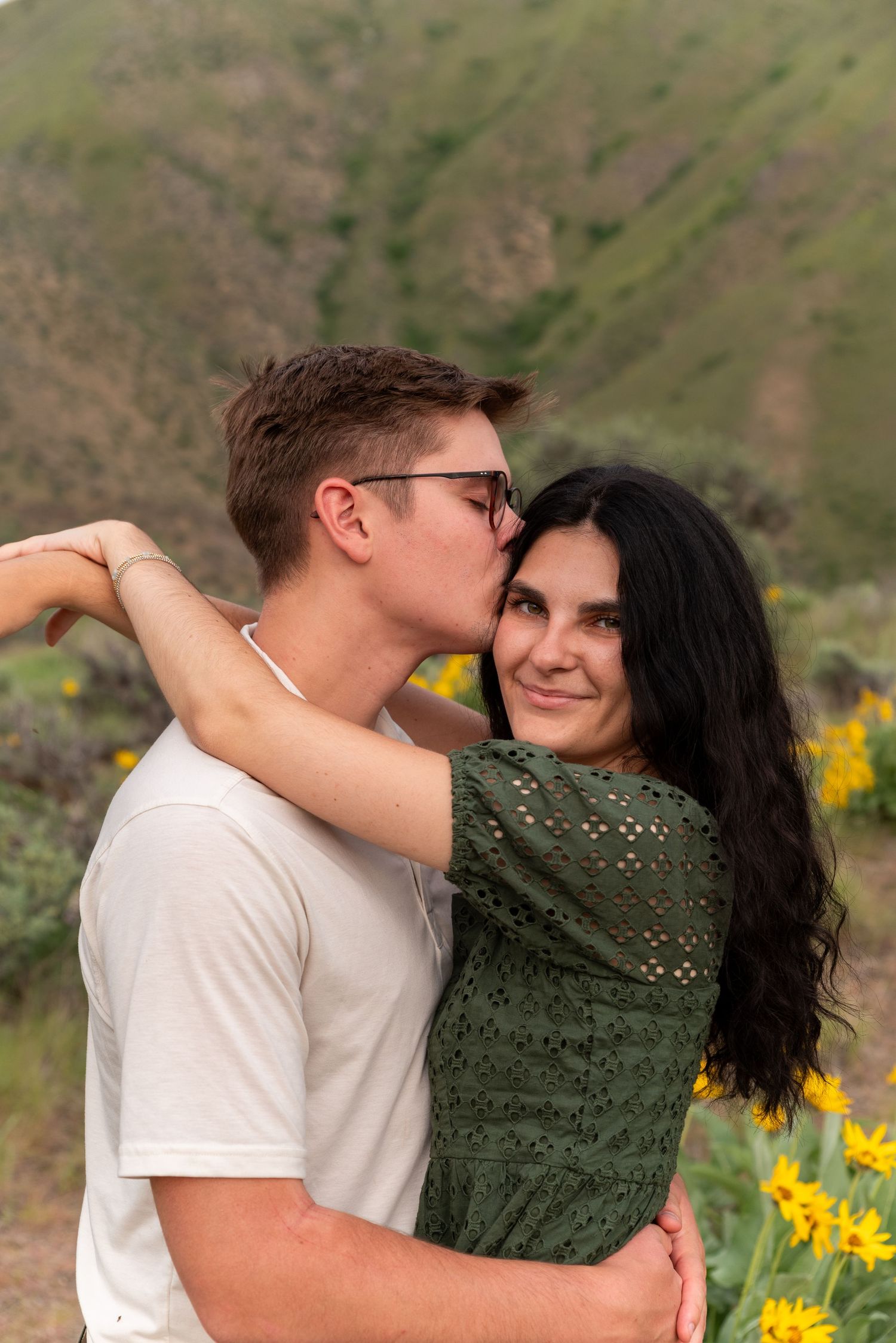 A couple embraces among yellow wildflowers on a hillside in a series of progressive romantic shots.