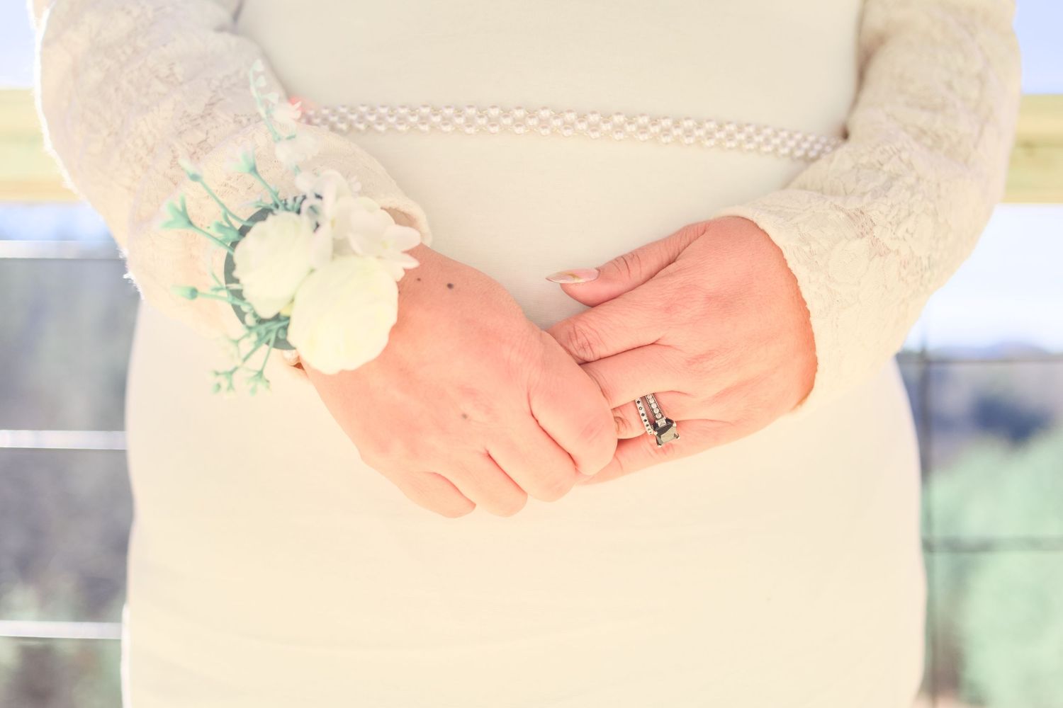 Close-up details of wedding rings and hands against a soft, natural background.