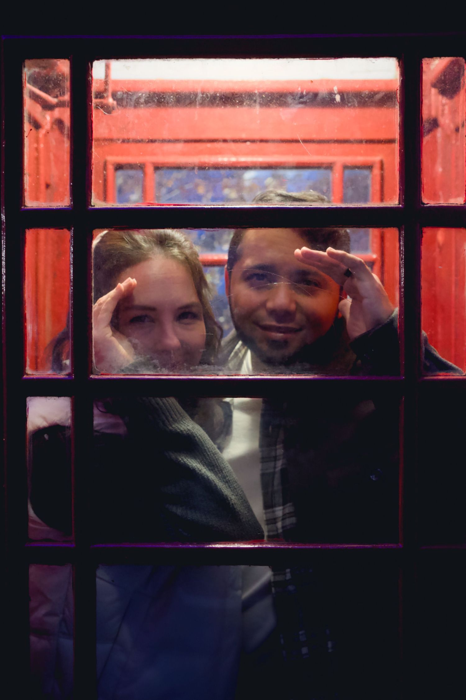 People peek through red-framed windows with playful expressions.