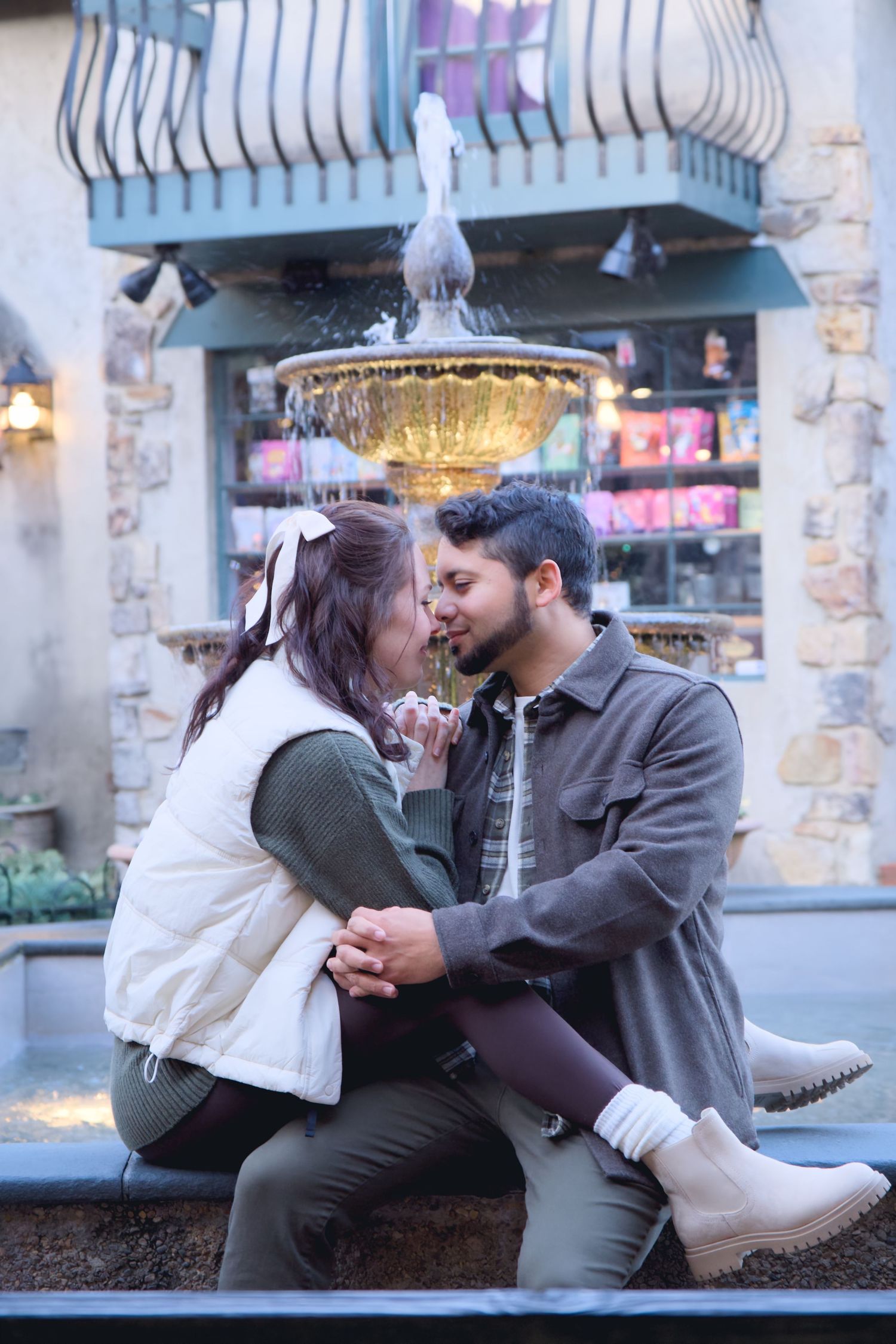 Romantic couple sharing an intimate moment near a decorative fountain in a charming outdoor setting.