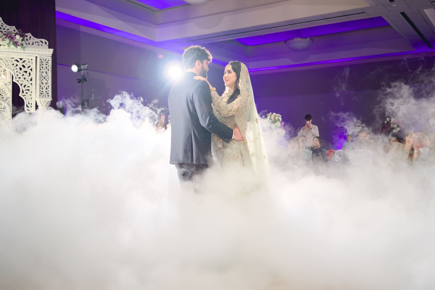 Dramatic first dance scene with fog effects and purple lighting at an elegant wedding reception.