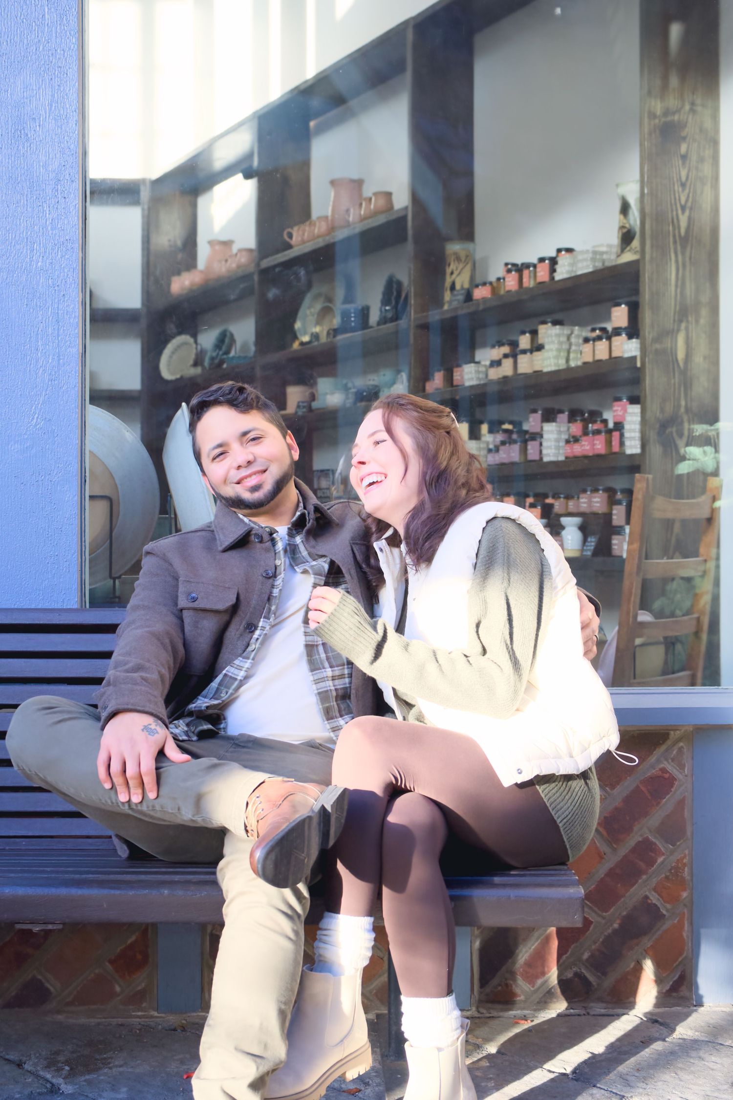 Couple sharing a joyful moment while sitting on a bench in front of a storefront.