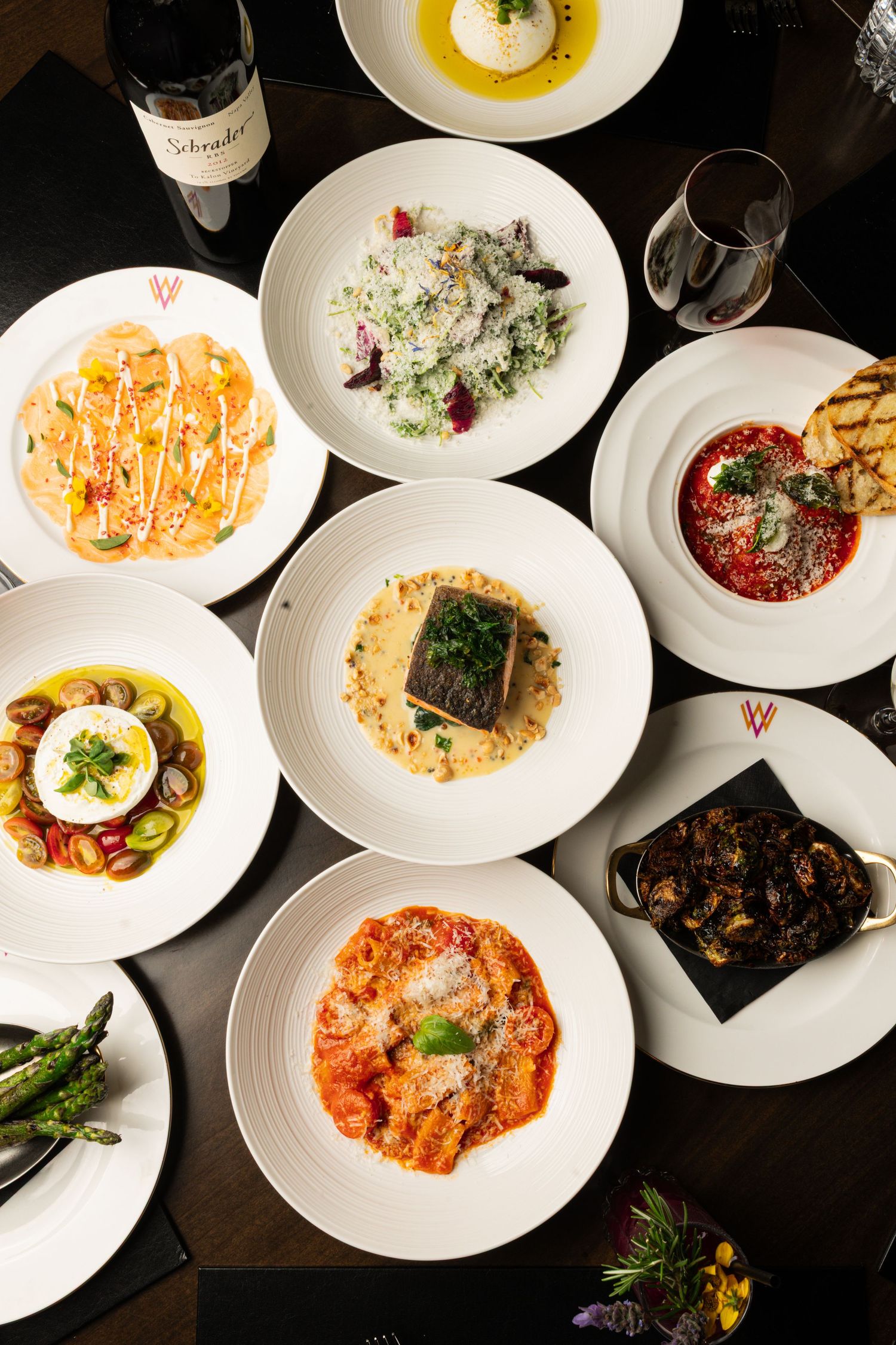 Collection of beautifully plated white dishes featuring pasta, seafood and meat courses.
