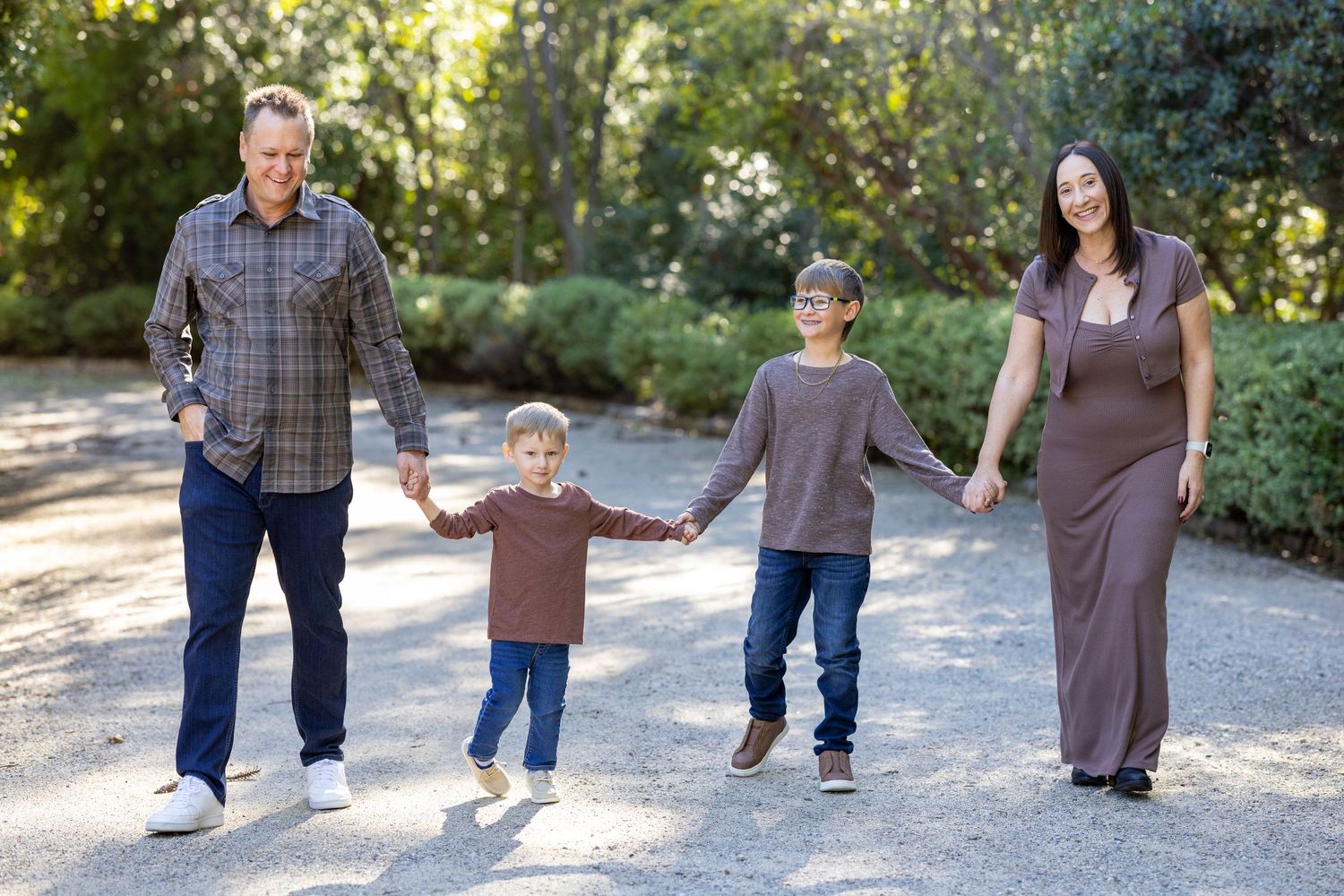 Family walking together on a gravel path through a garden setting.