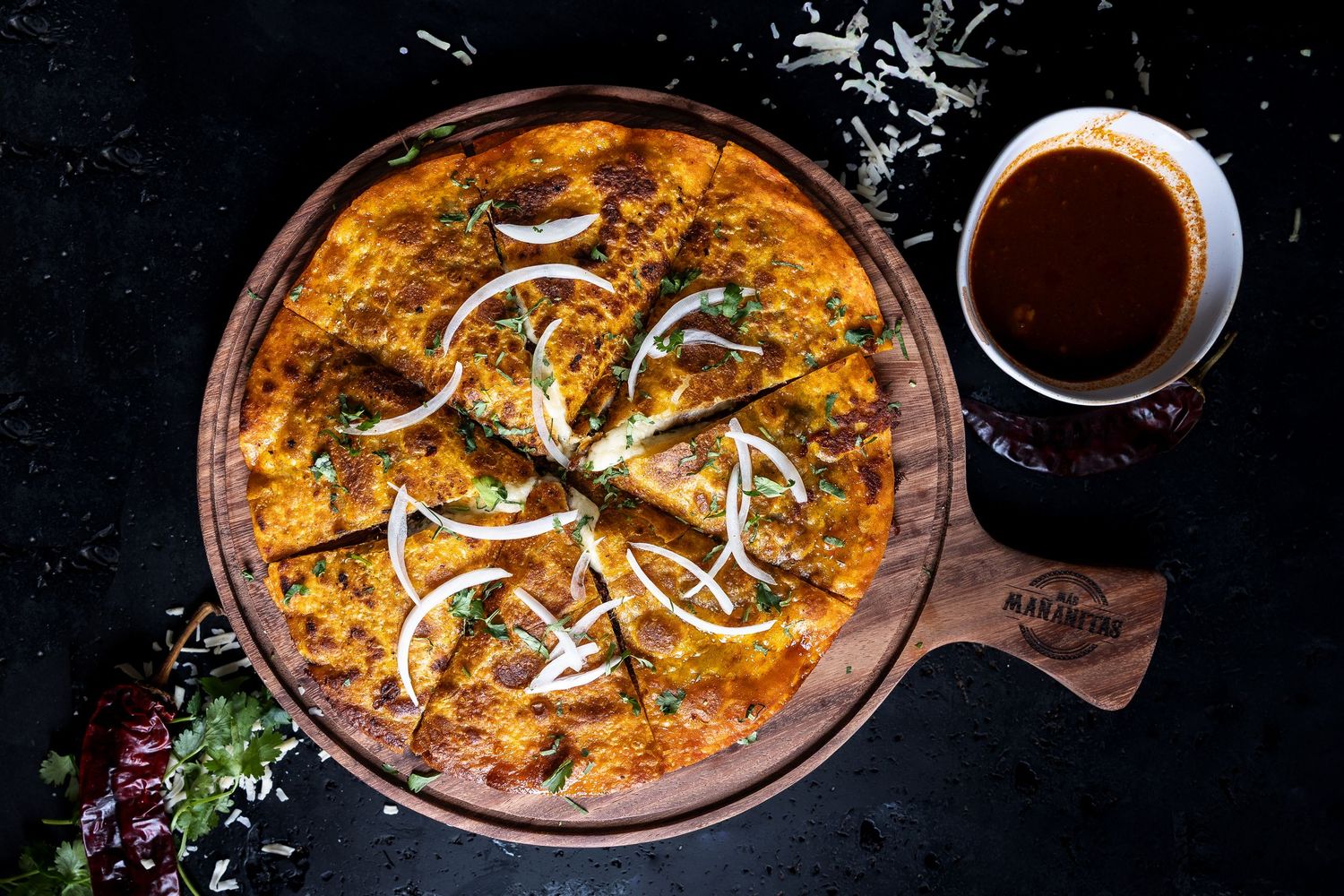 Sizzling curry dish in cast iron pan with garnishes and accompaniments.