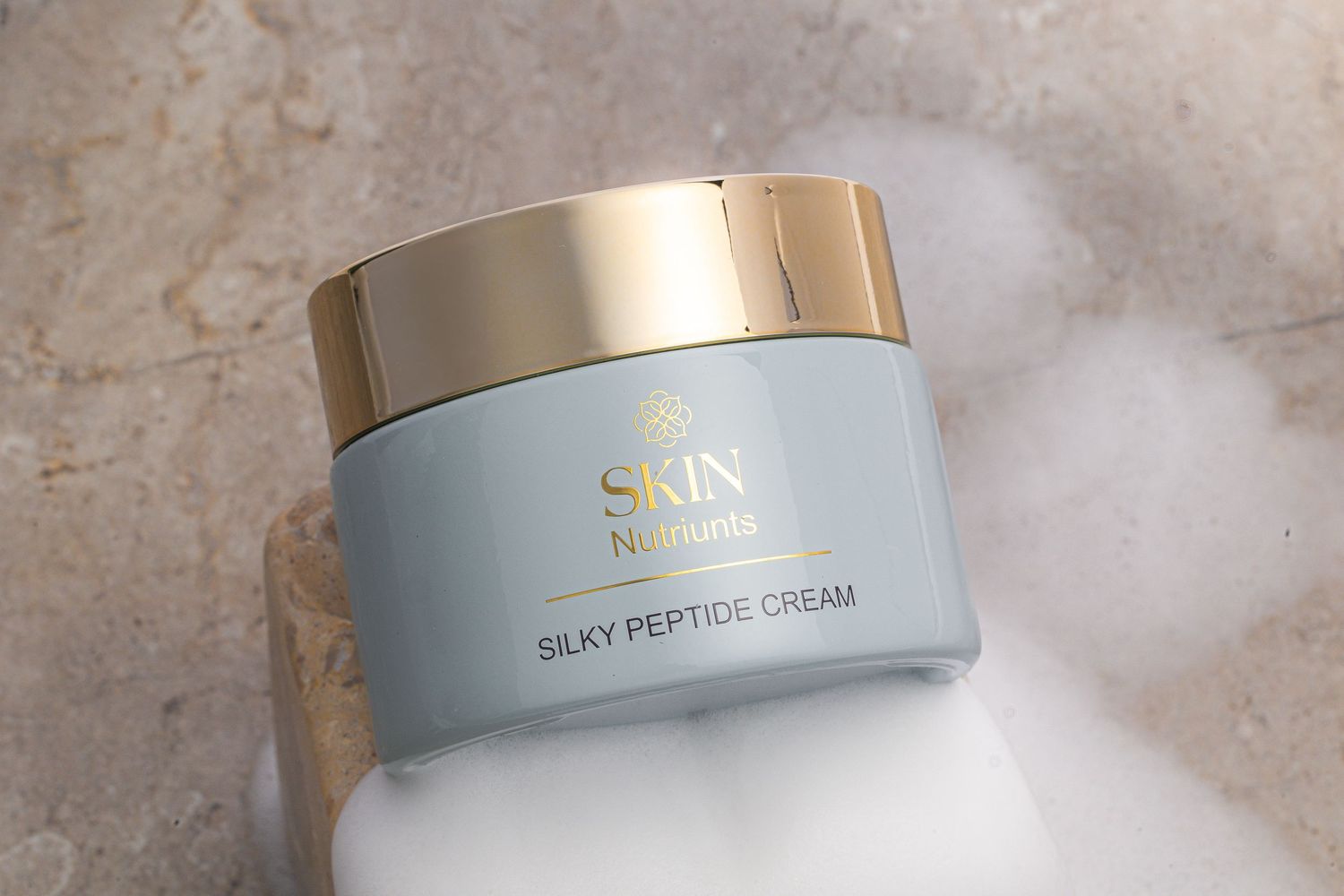 Premium skincare cream jars with gold accents arranged on marble surface.