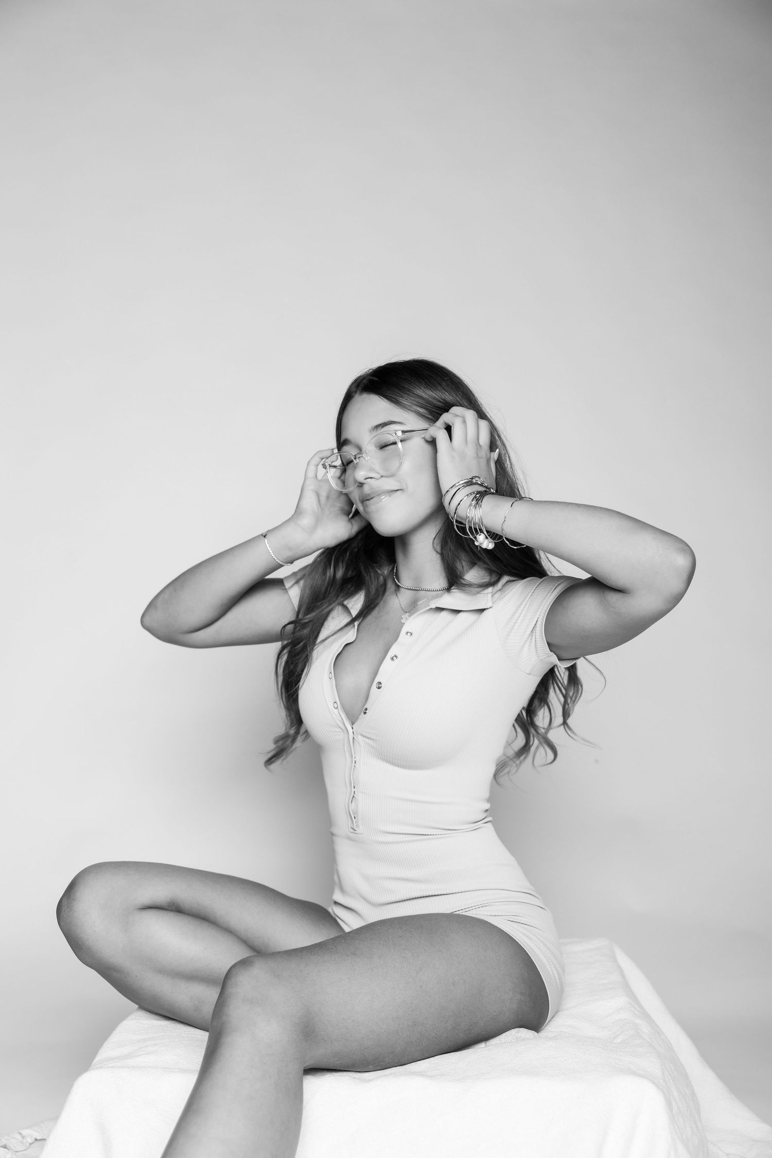 Woman in white outfit doing dynamic poses against grey studio background.