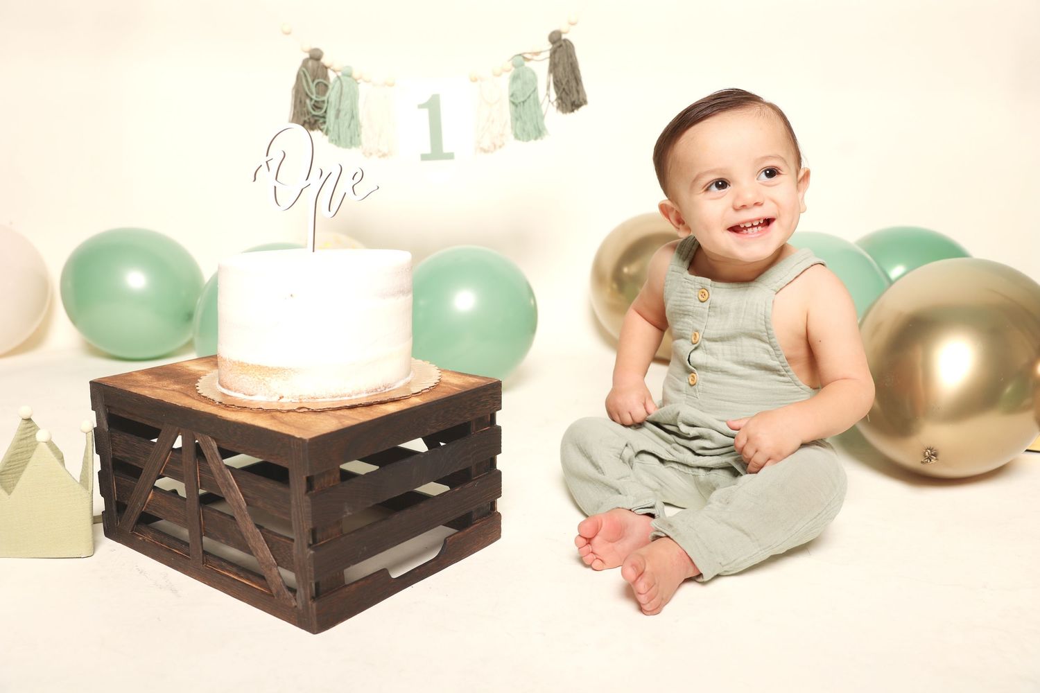 Baby milestone photoshoot with mint and gold balloons and wooden crate props.