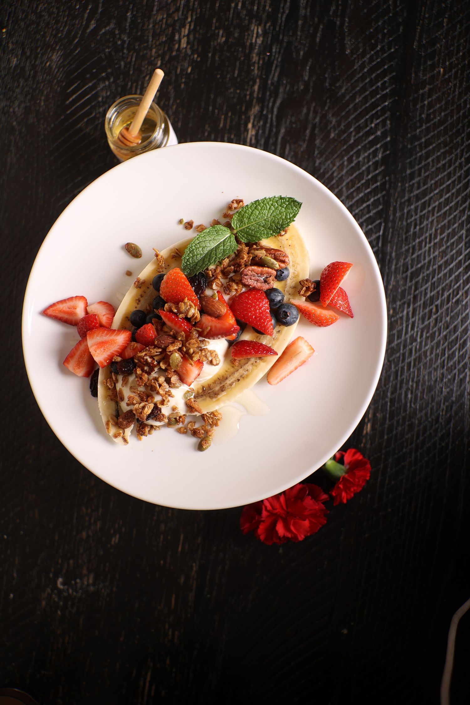 Fresh strawberries and other fruits artfully plated on white dishes with elegant garnishes.