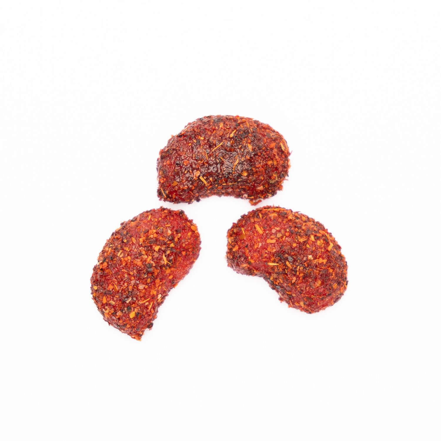 Three spicy red-coated snack pieces arranged on white background.