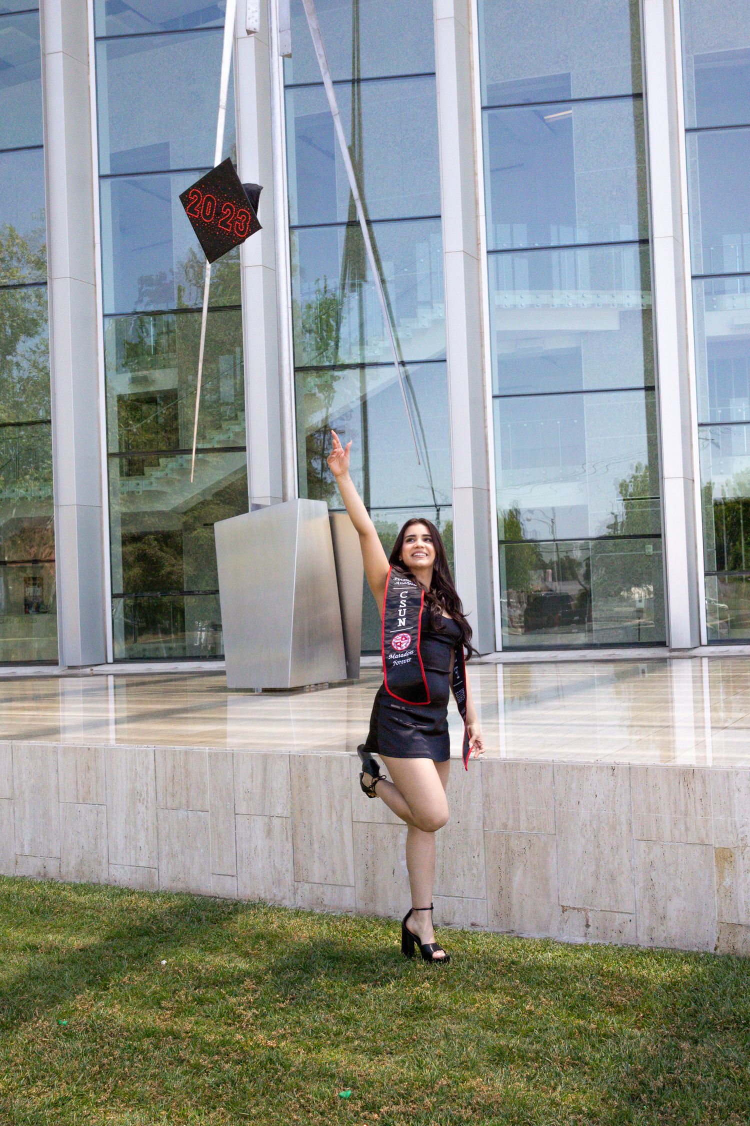 A person in athletic wear reaches up towards a star decoration outside a modern building.