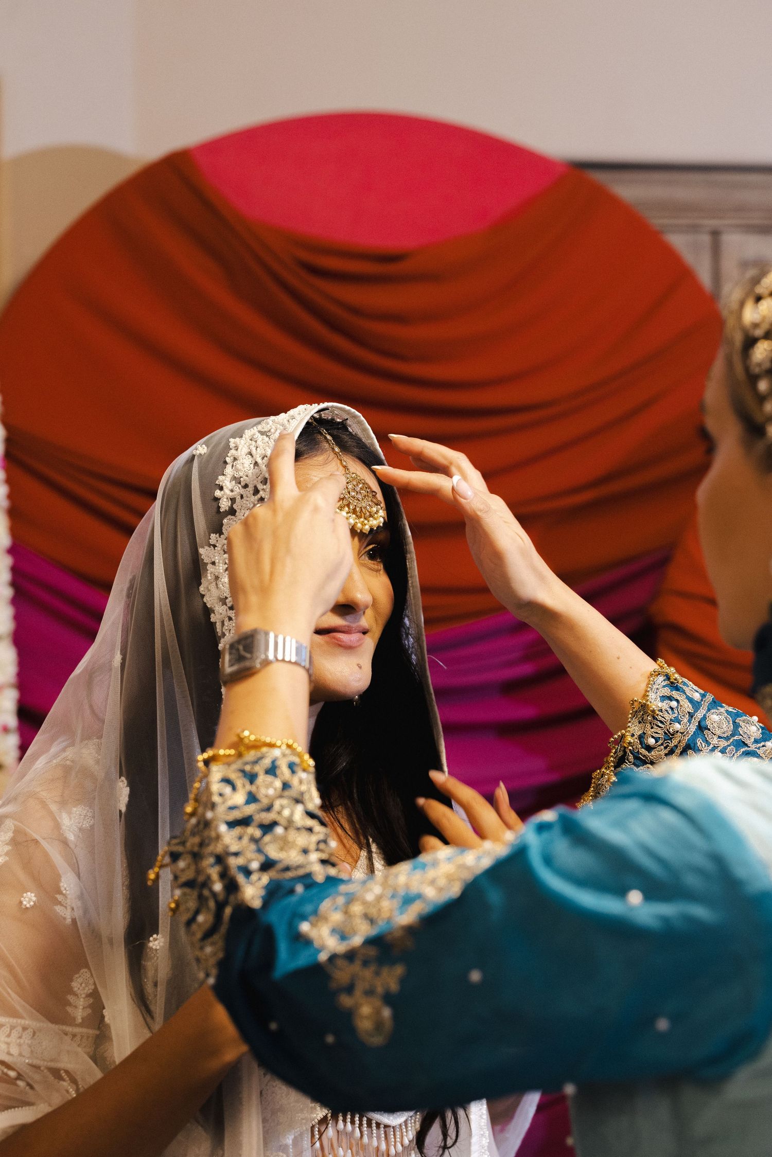A series of images showing someone adjusting a traditional blue and silver embellished hijab with a veil.
