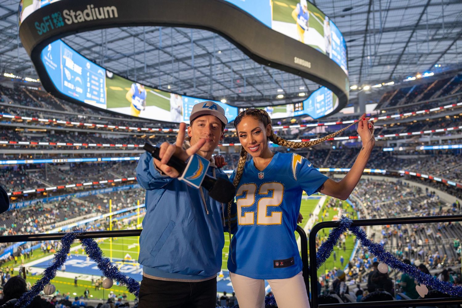 Two sports fans celebrate together while watching a game in a packed stadium.