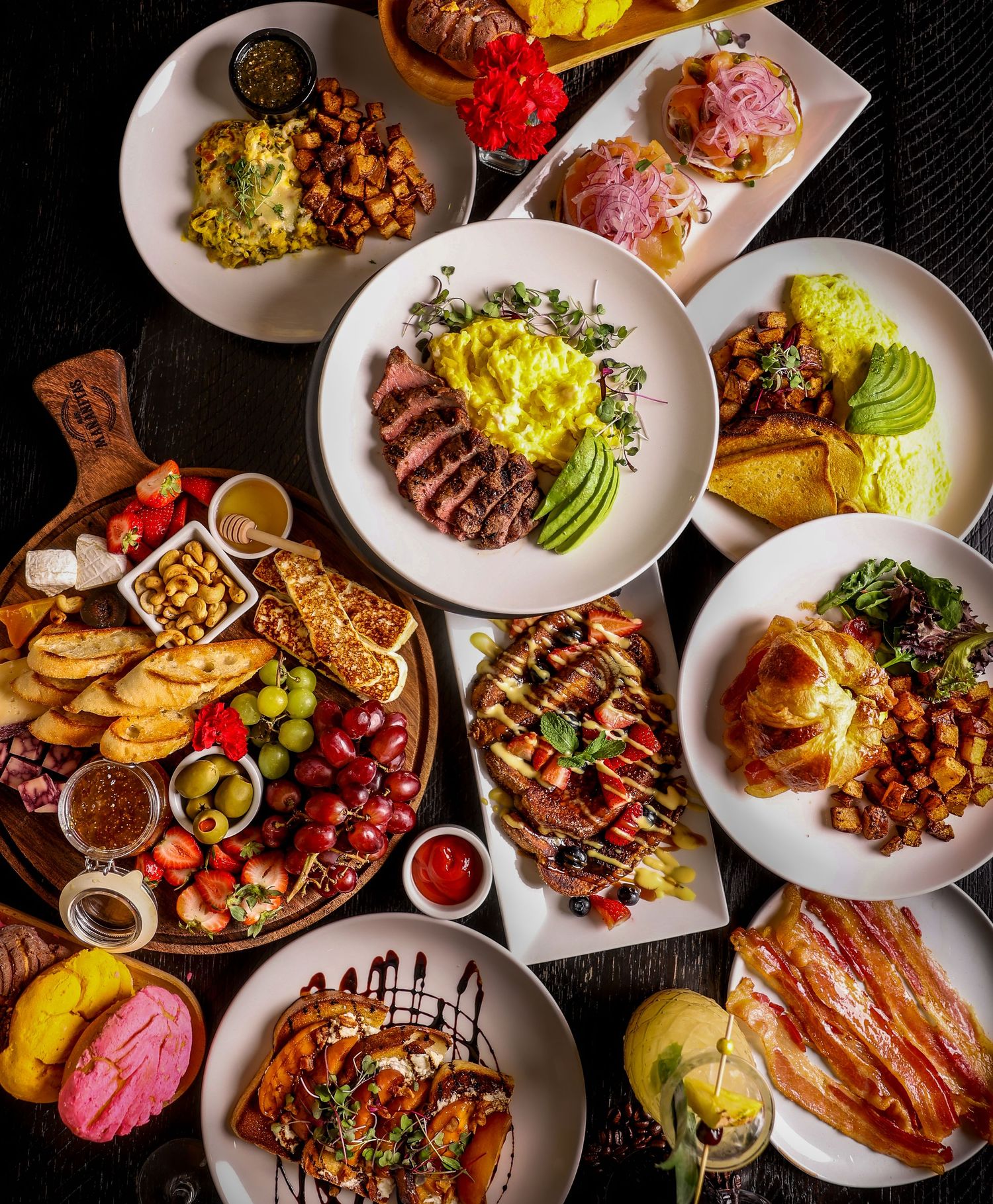 Overhead view of various grilled meats, appetizers and sides arranged on white plates.