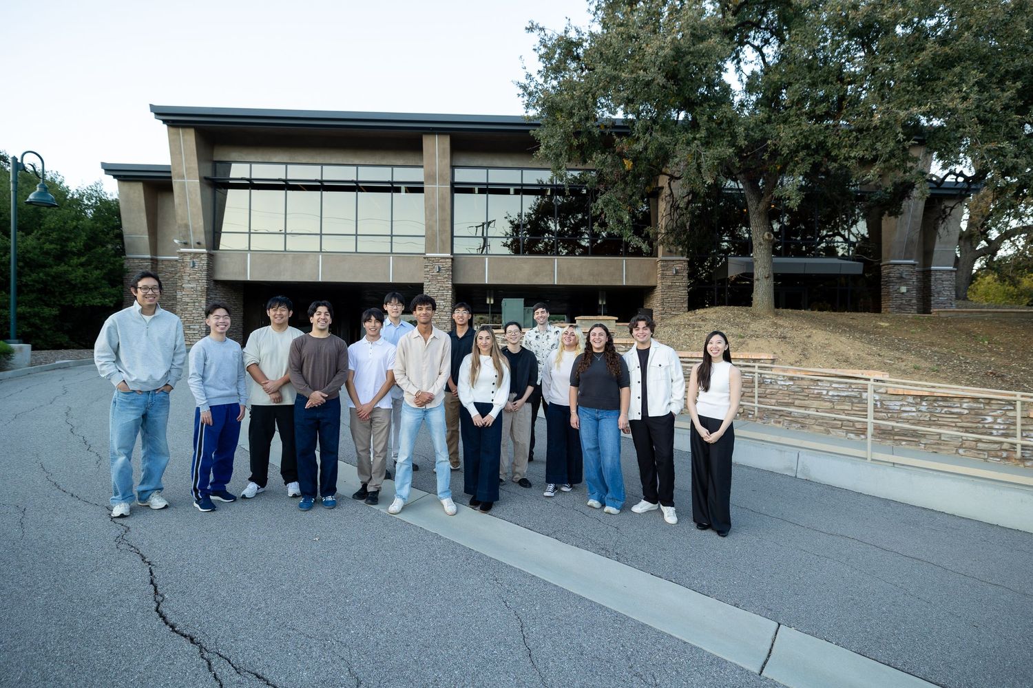 Large group of people arranged in a line outside a modern building.