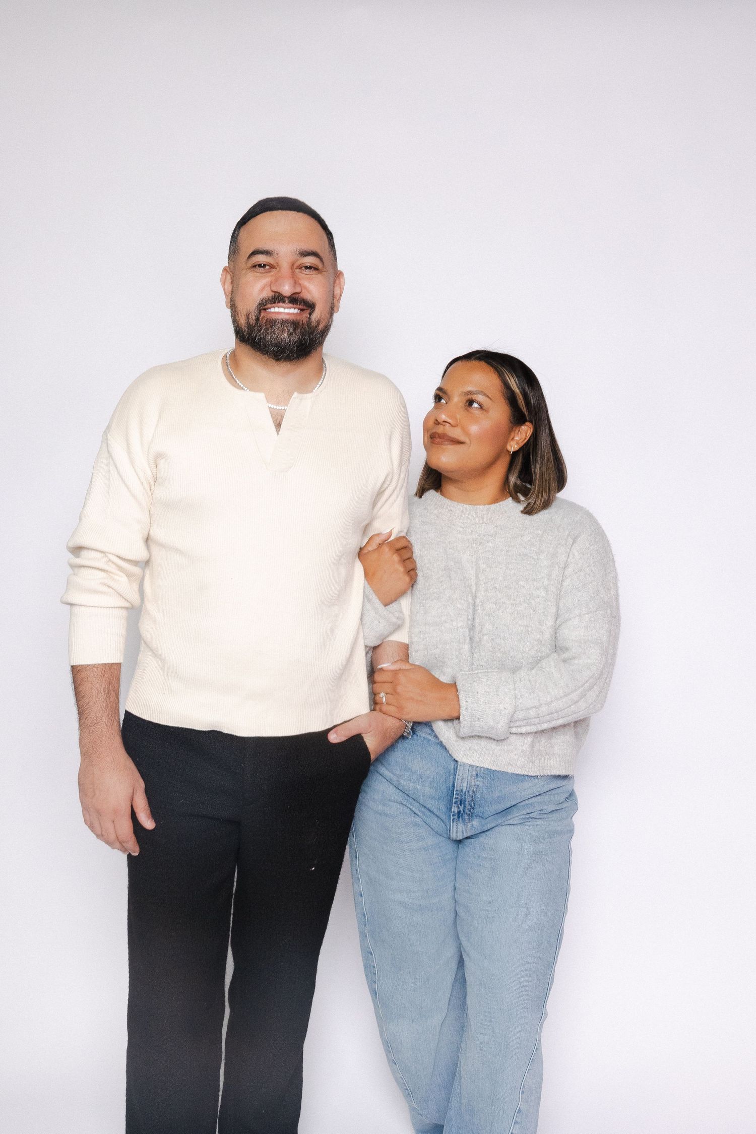 Couple in casual wear sharing intimate moments against white backdrop.