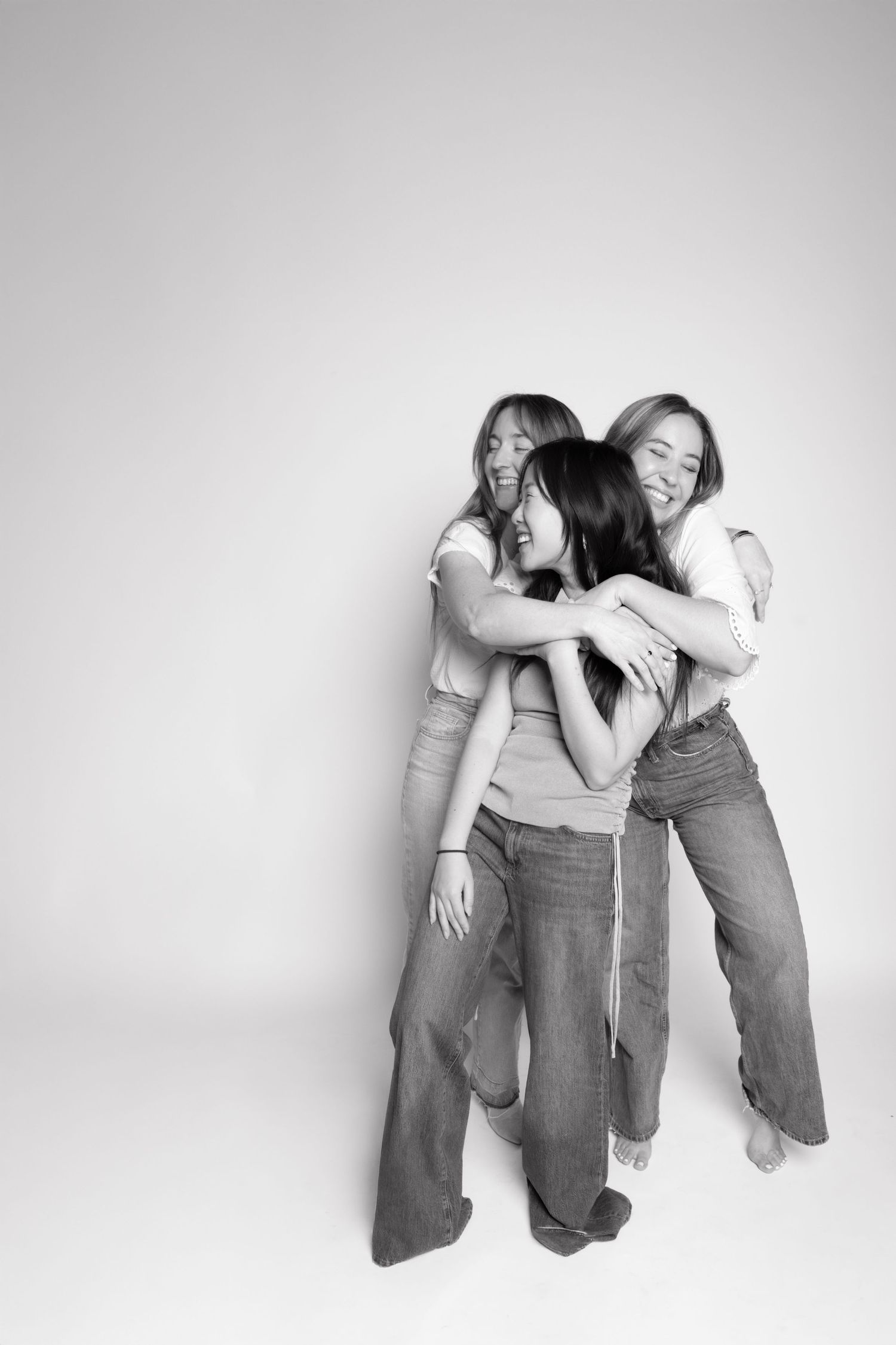 Group of friends in casual wear laughing and embracing in black and white photo series.
