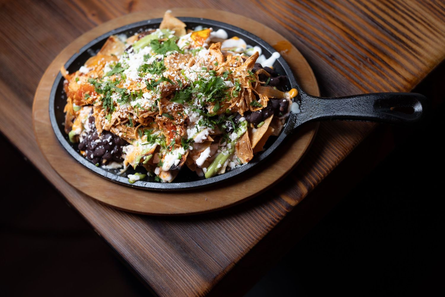 Mexican-style dish served on a dark plate with fresh herbs and toppings.