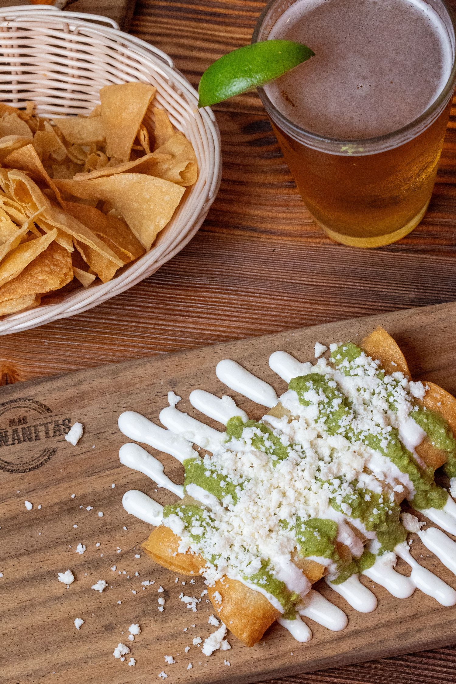 Mexican street corn dish drizzled with white sauce and cotija cheese on a wooden serving board.