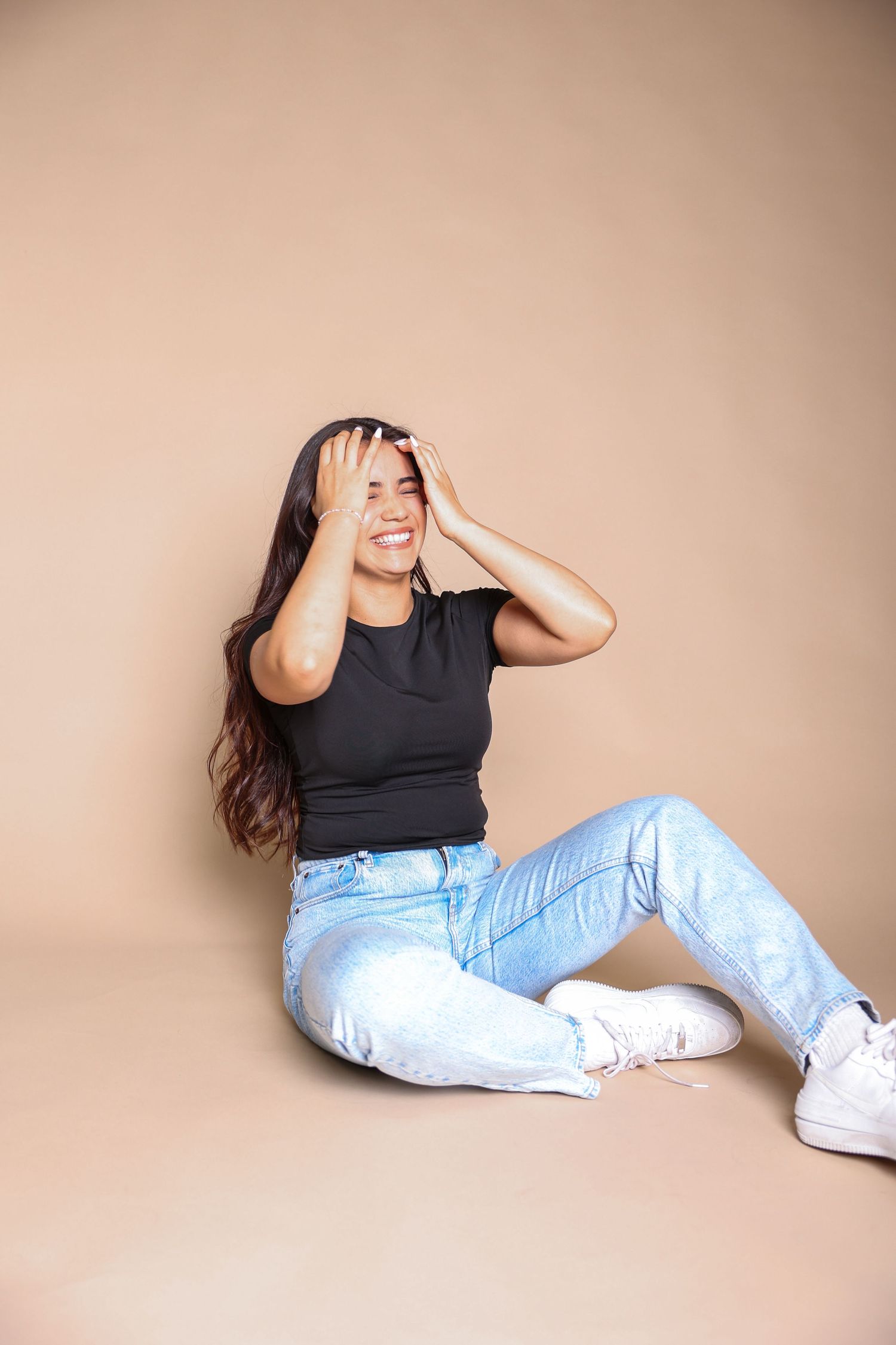 Person in casual attire and white sneakers posing against beige background.