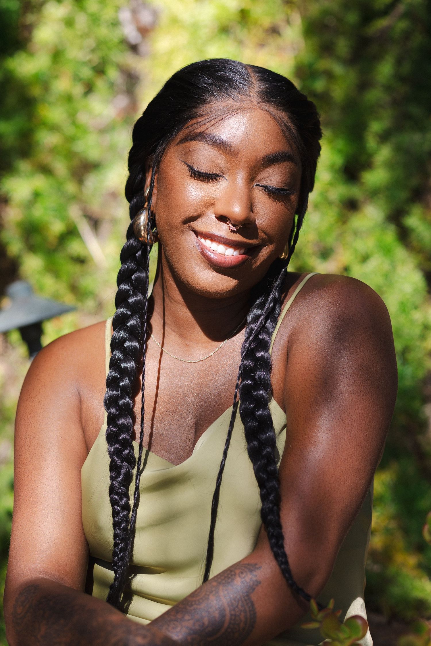 Portrait series showing braided hairstyles against a sunny natural green background.