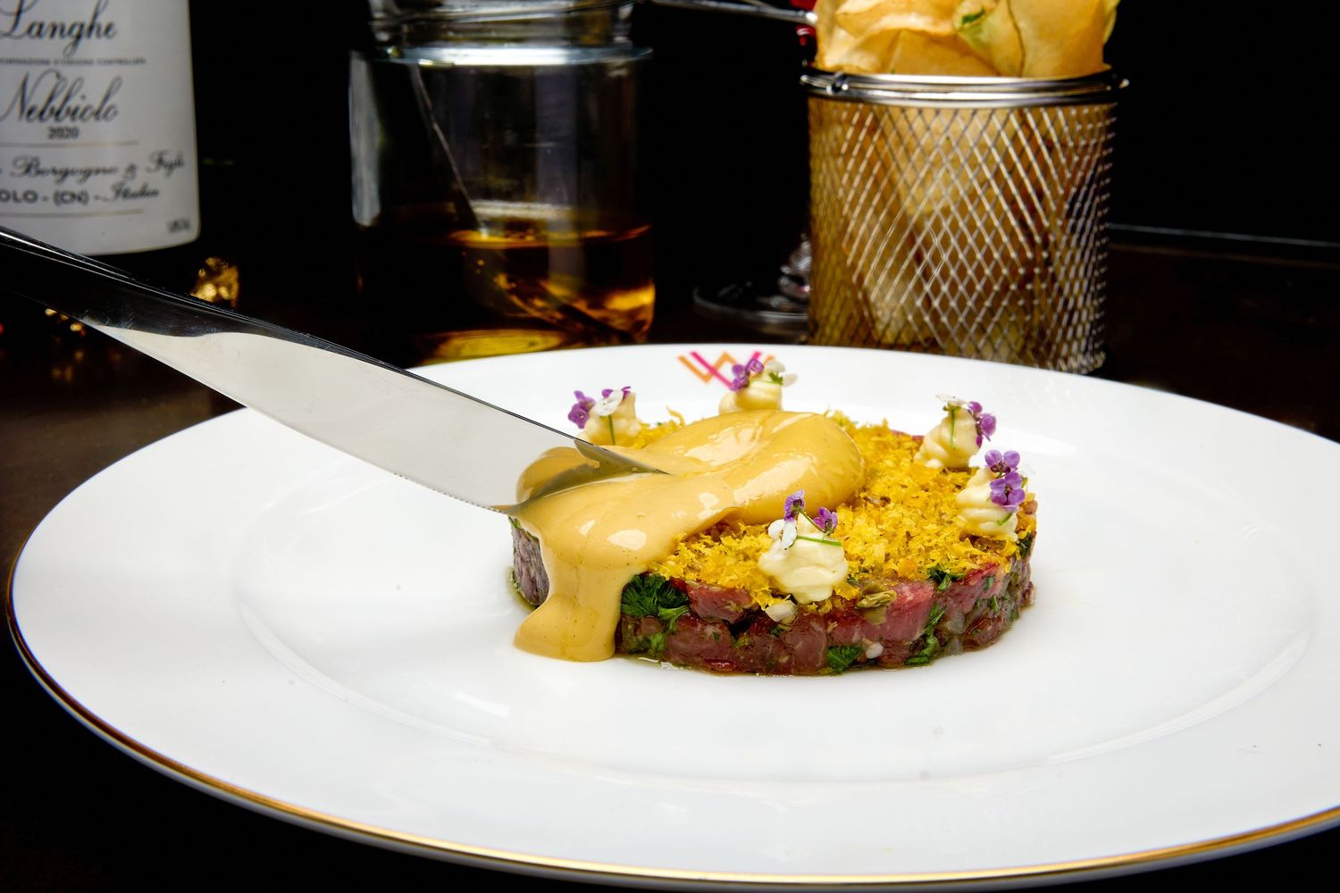 Elegant plated dishes with colorful garnishes and sauces on white dinnerware.
