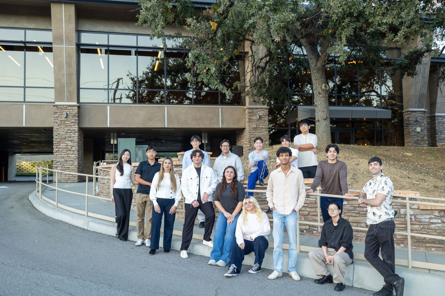 Students gathered outside a contemporary campus building for a group photo.