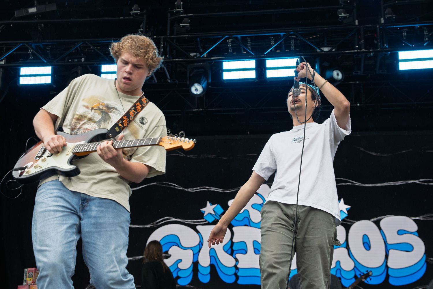 Guitarist and vocalist performing energetically on stage at outdoor festival.
