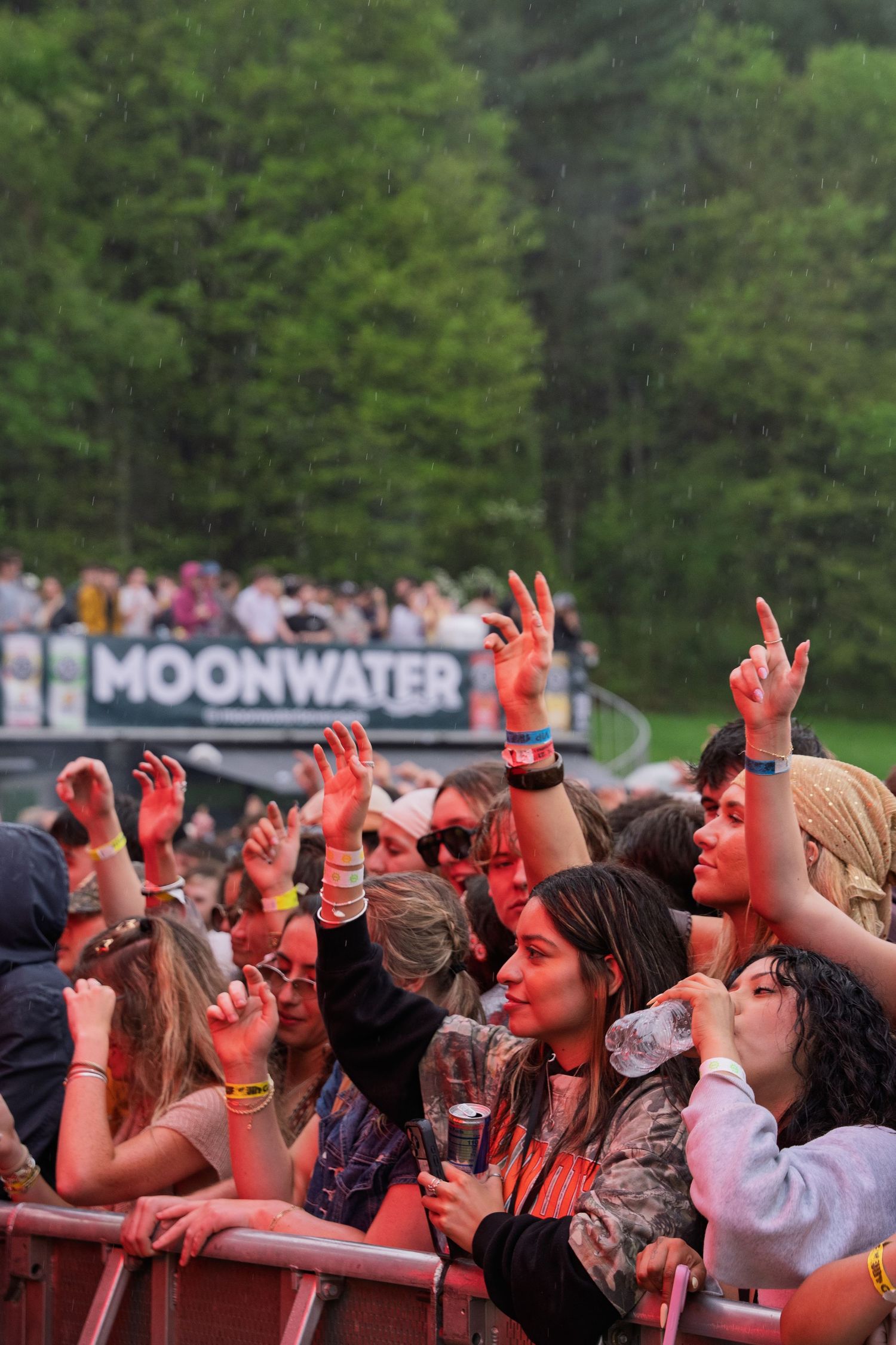 Excited festival crowd with raised hands near Moonwater branded stage at an outdoor music event.