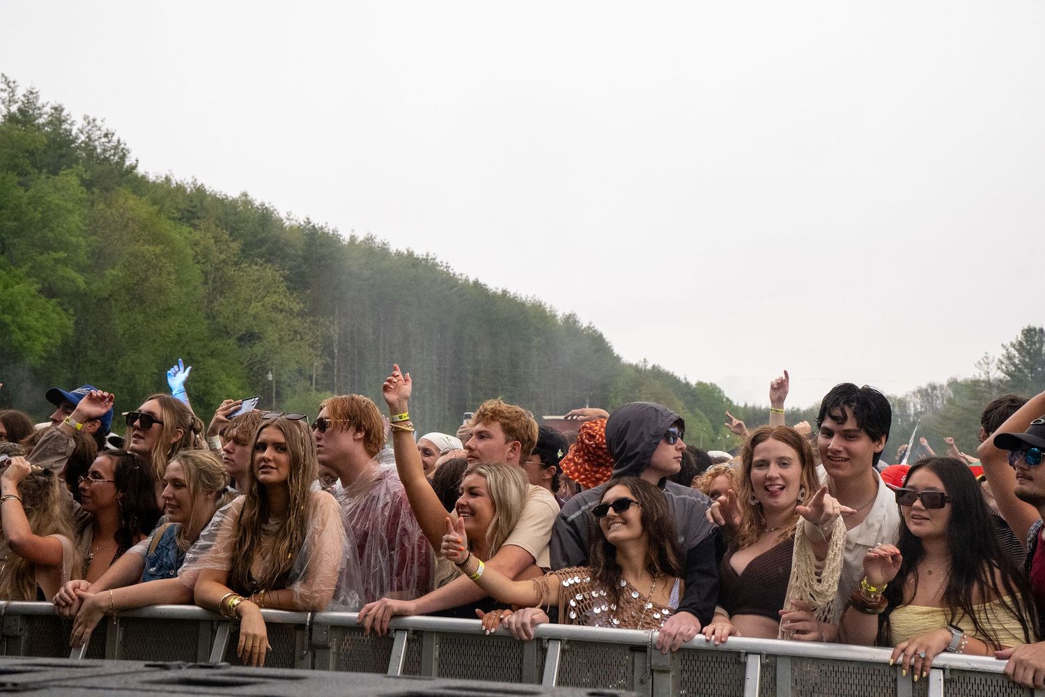 A diverse crowd of excited fans watches a live performance at an outdoor music festival.