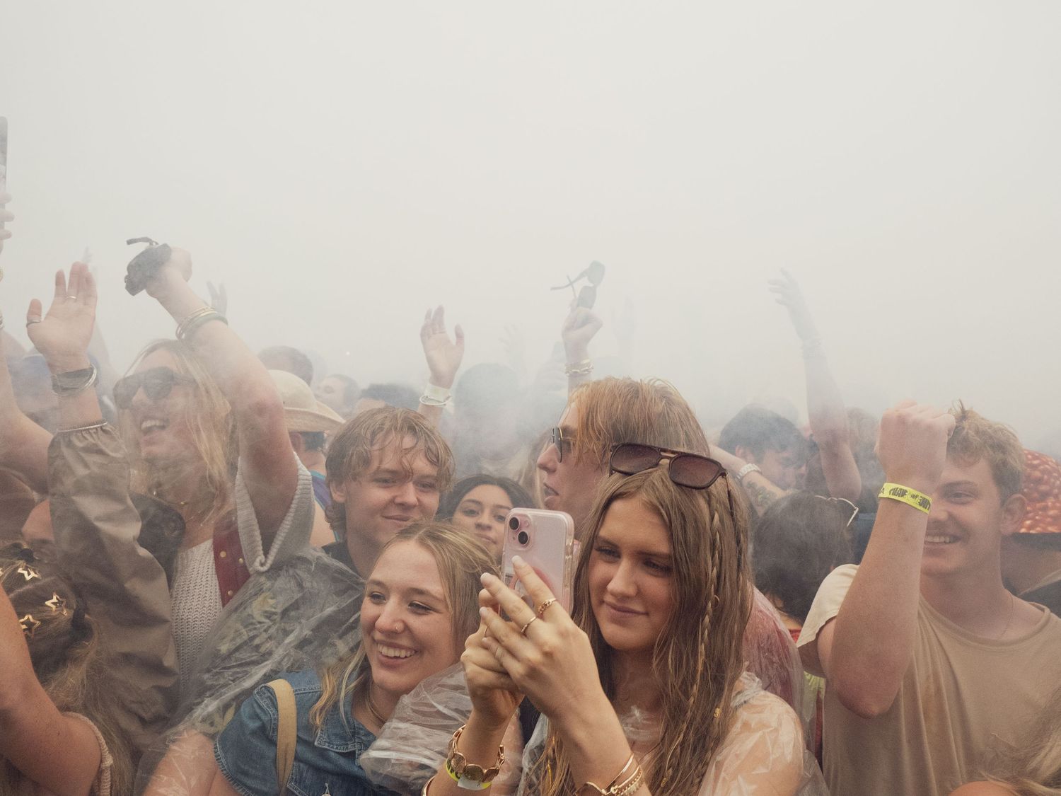 Wet festival crowd cheering in fog or mist at outdoor music event.