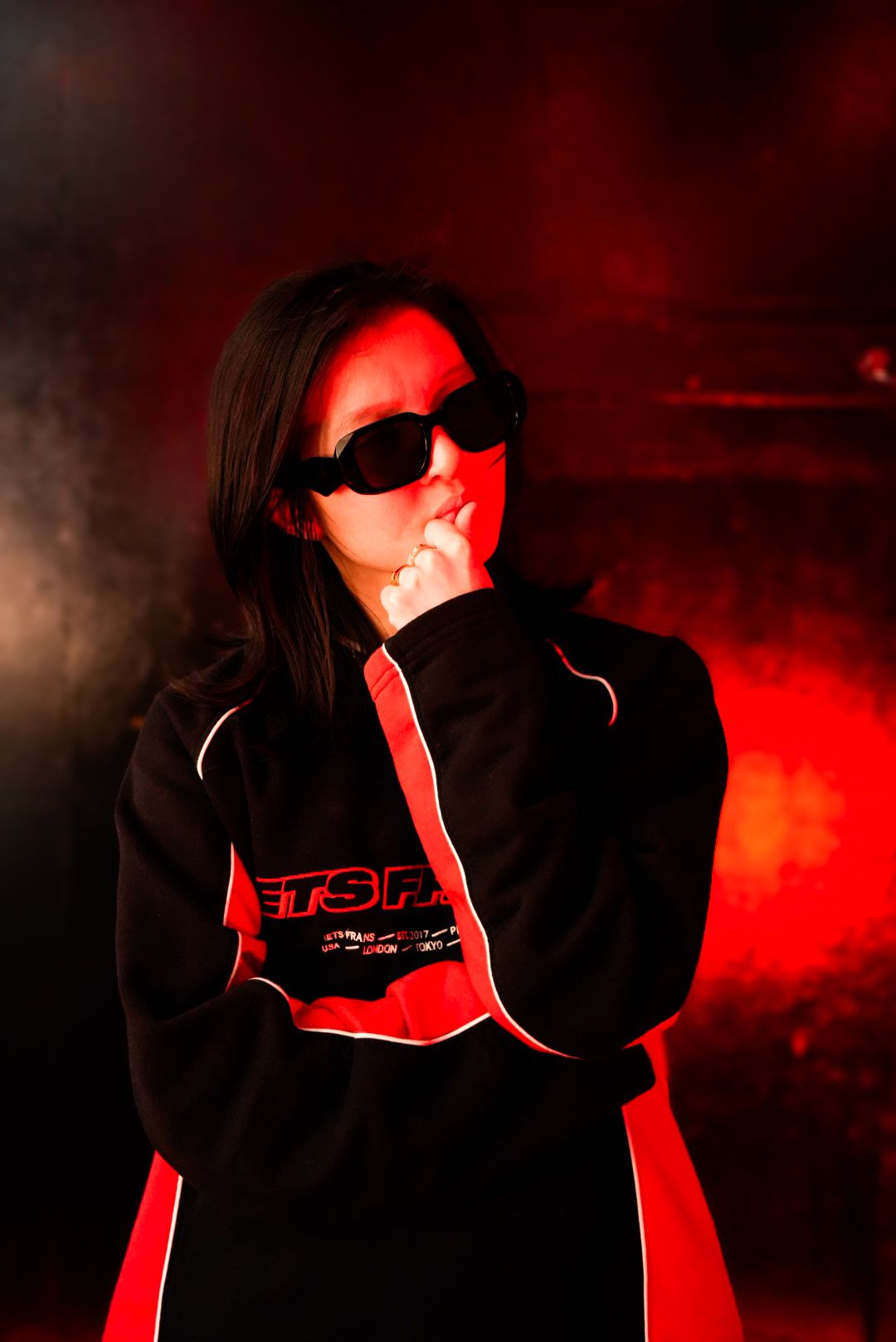 Person in black and red Jets Frans jacket posing in smoky red light.
