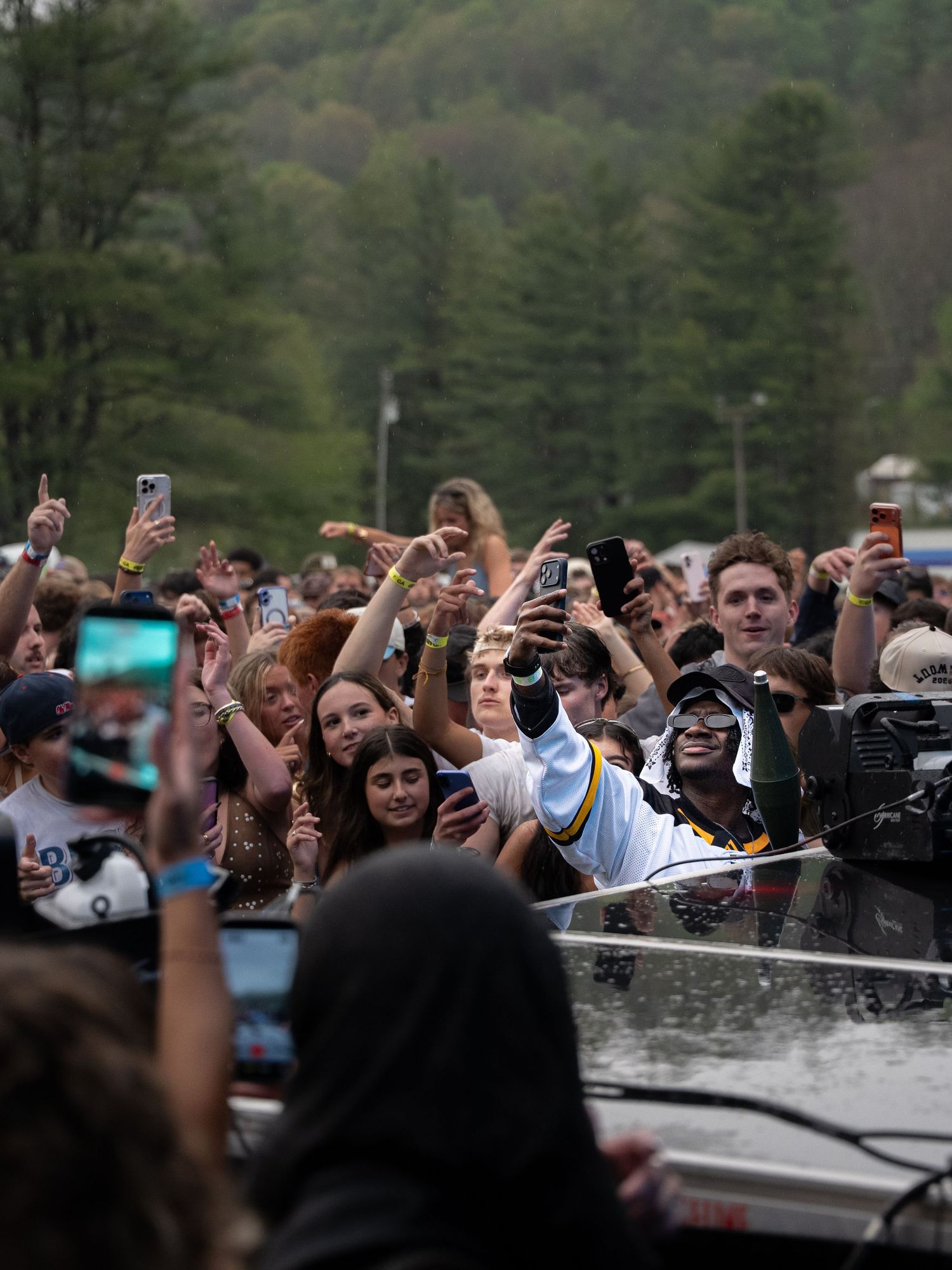 Excited concert fans hold up phones to capture a live outdoor music festival performance.