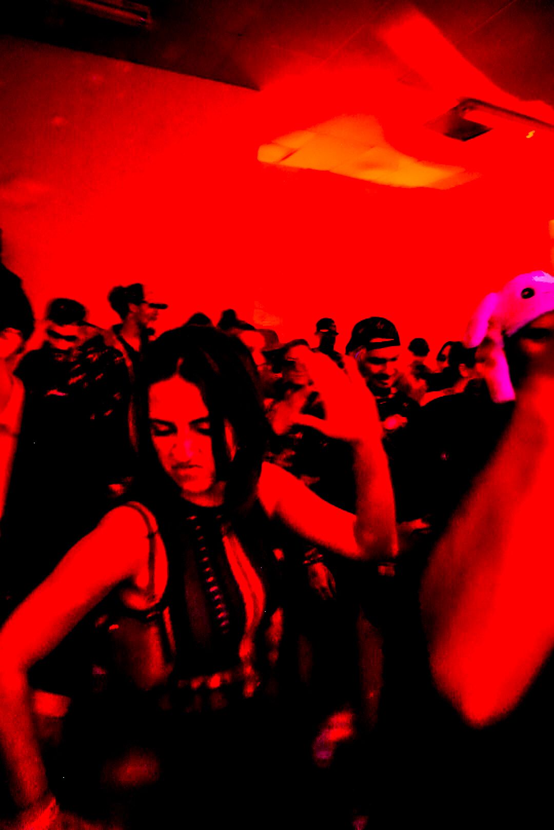 People dancing under red lights at a nightclub party.